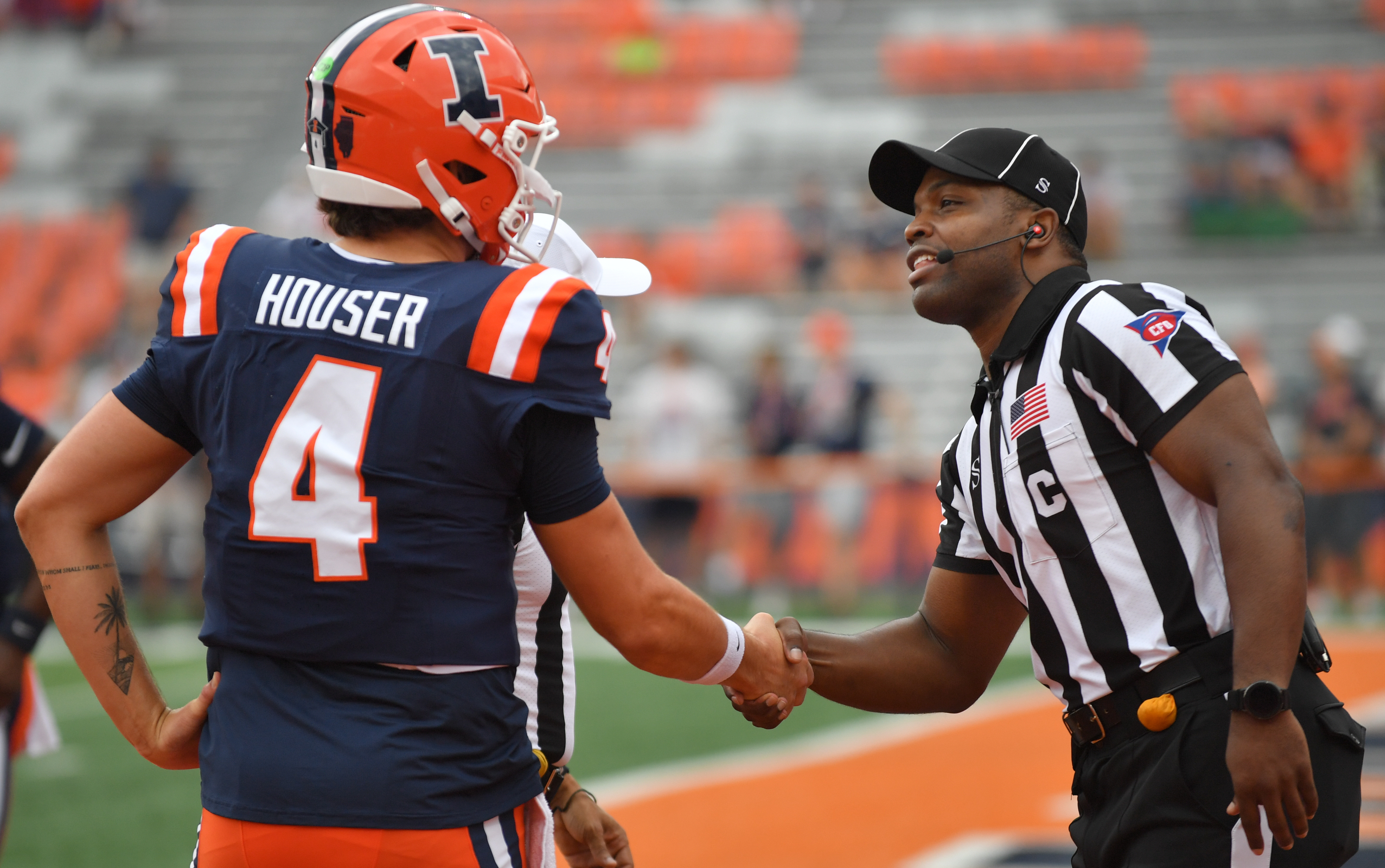 An official shakes hands with Illinois Fighting Illini quarterback Katin Houser (4) before the game as he is featured in our Illinois vs. Ohio State prediction.
