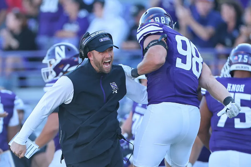 Interim head coach David Braun of the Northwestern Wildcats celebrates a touchdown with Duke Olges #98 as we make our Utah vs. Northwestern prediction and pick for the Las Vegas Bowl on Saturday.
