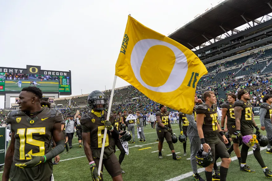 Wide receiver Isaah Crocker of the Oregon Ducks carries a flag for teammate Spencer Webb after their game against the Brigham Young Cougars.
