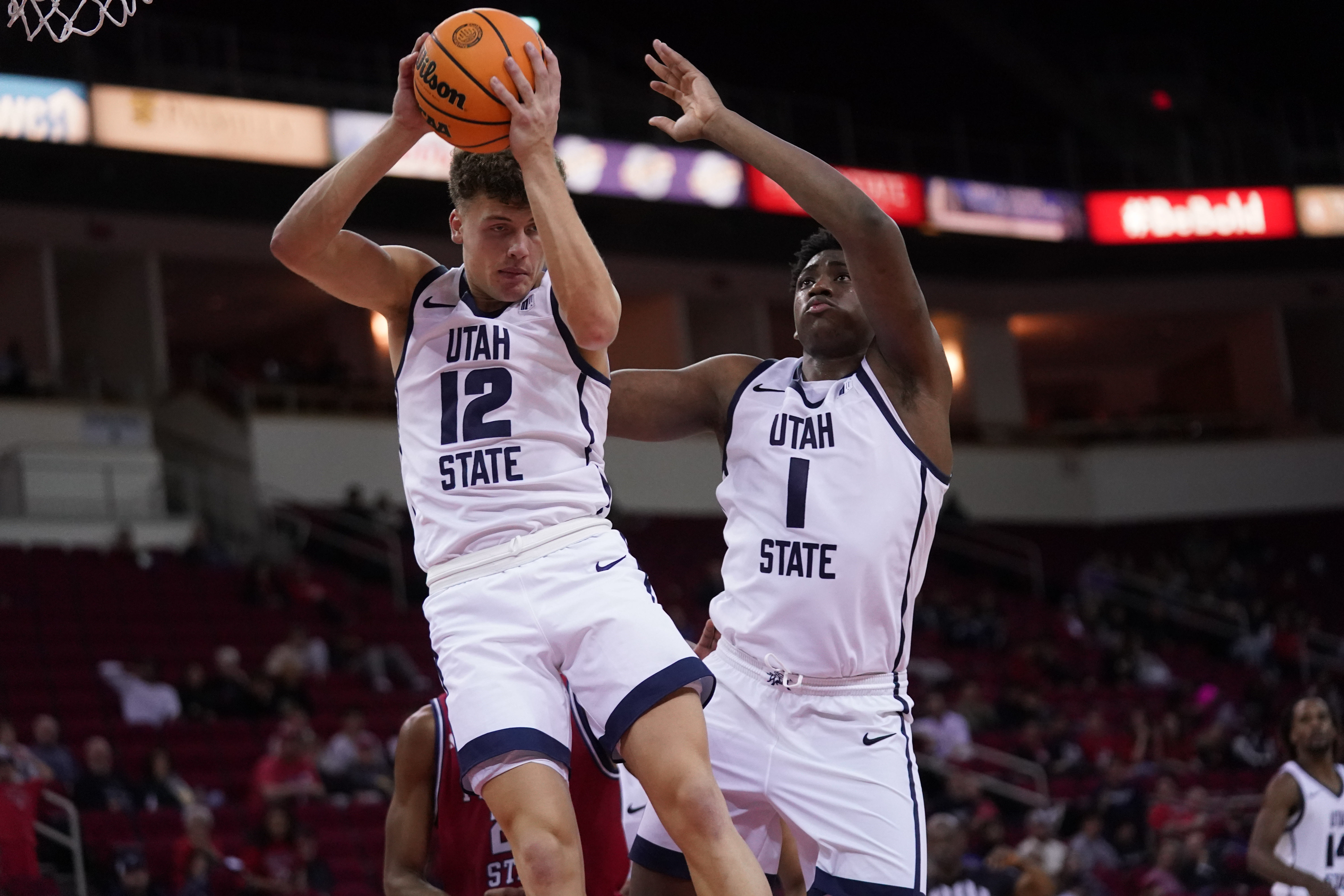 Utah State Aggies guard Mason Falslev (12) holds onto a rebound next to forward Great Osobor (1) as we break down our Utah State vs. Arizona prediction.