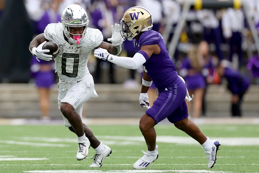 Bucky Irving #0 of the Oregon Ducks carries the ball against Jabbar Muhammad #1 of the Washington Huskies as we make our Oregon vs. Washington Pac-12 Championship player props picks and predictions.