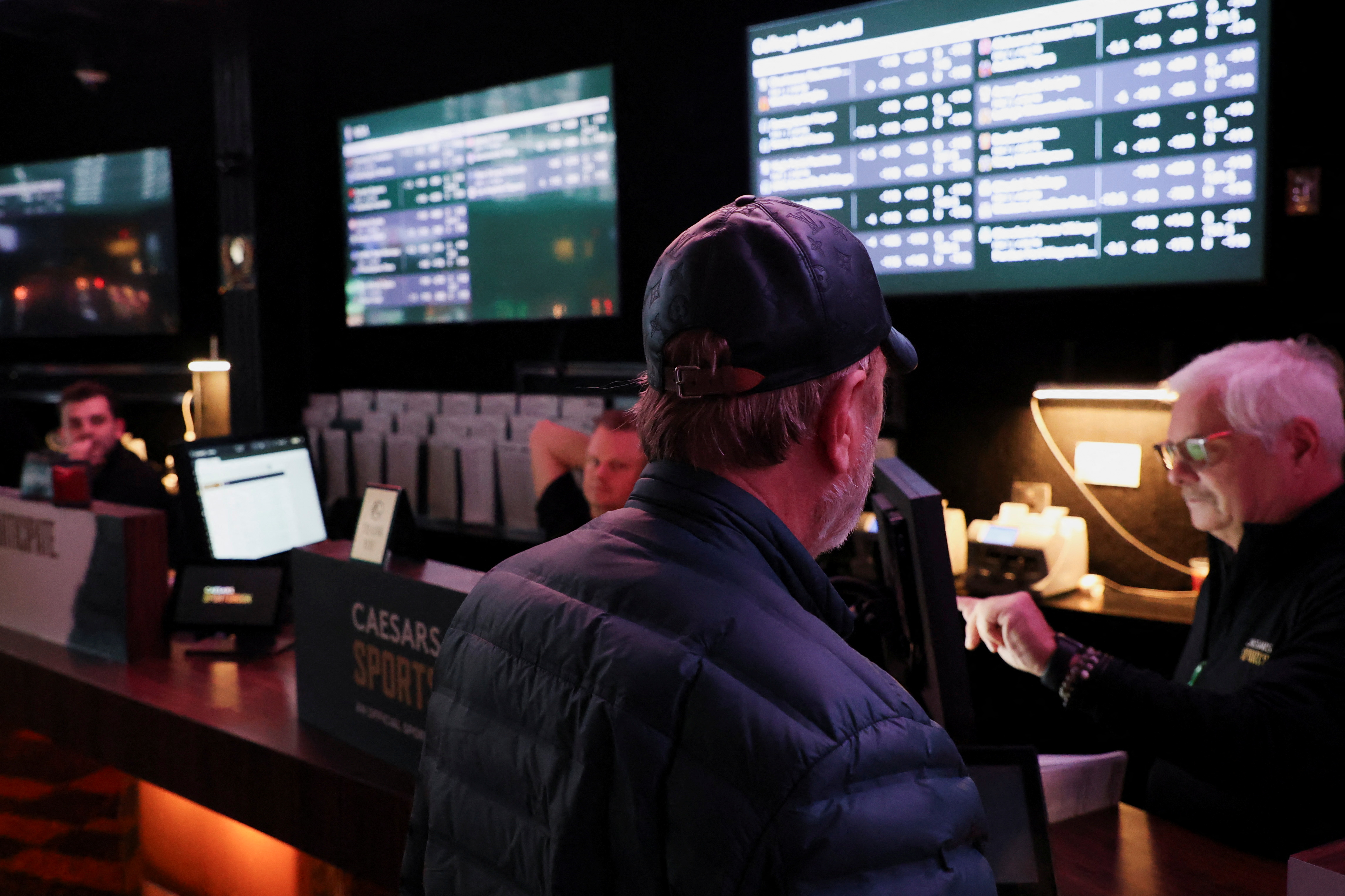 A man speaks with a cashier at the sportsbook area of Caesars Palace.