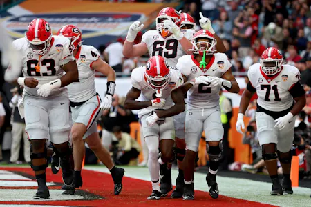 Kendall Milton of the Georgia Bulldogs celebrates with teammates after scoring a touchdown against the Florida State Seminoles during the Capital One Orange Bowl. Georgia leads the way for the College Football Projected Win Totals. 