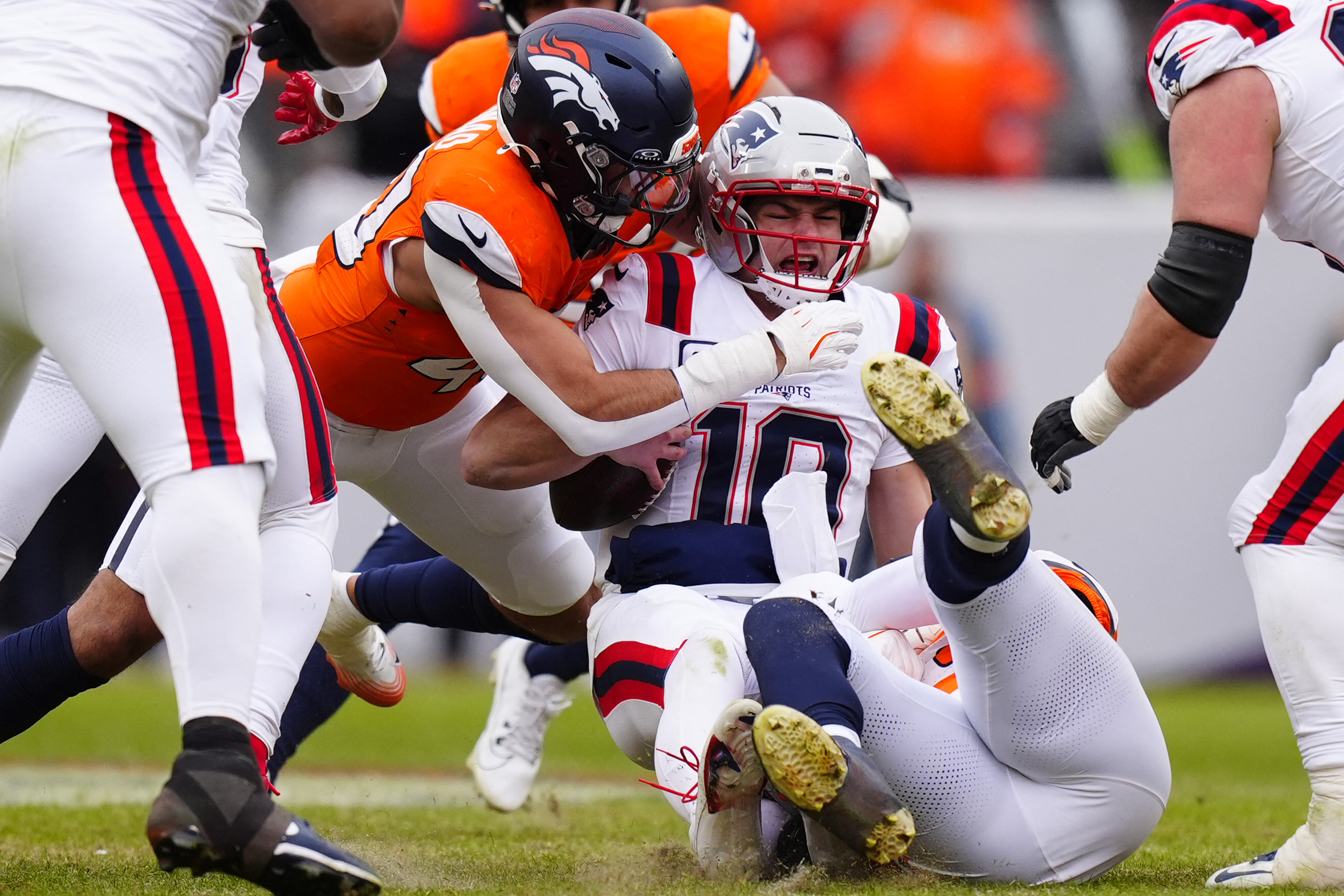 Denver Broncos defensive end Zach Allen (99) and linebacker Justin Strnad (40) tackle New England Patriots quarterback Drake Maye (10) as we break down the Patriots vs. Broncos stats for the 2026 AFC Championship.
