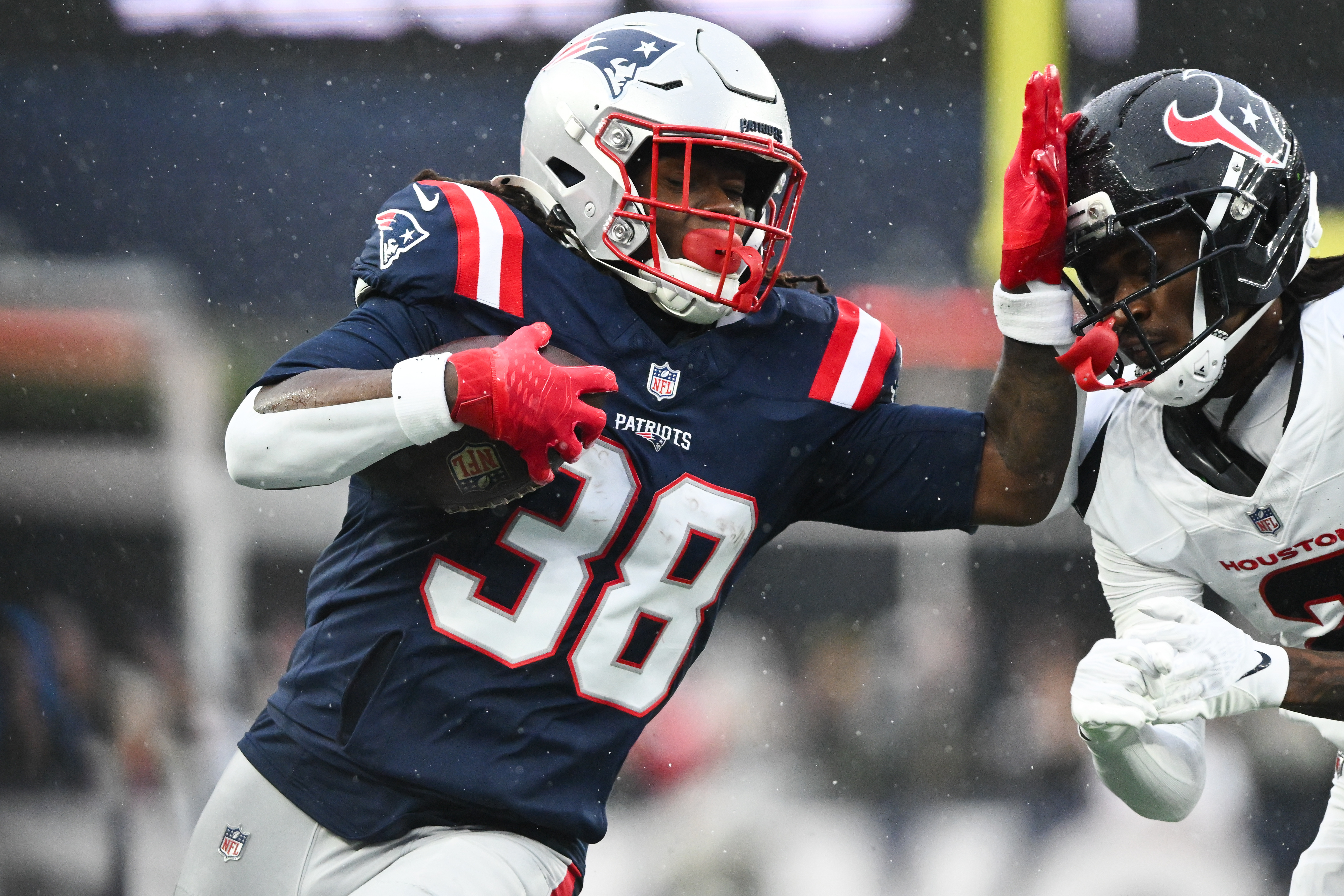 New England Patriots running back Rhamondre Stevenson runs with the ball as we make our best Patriots vs. Broncos expert picks.