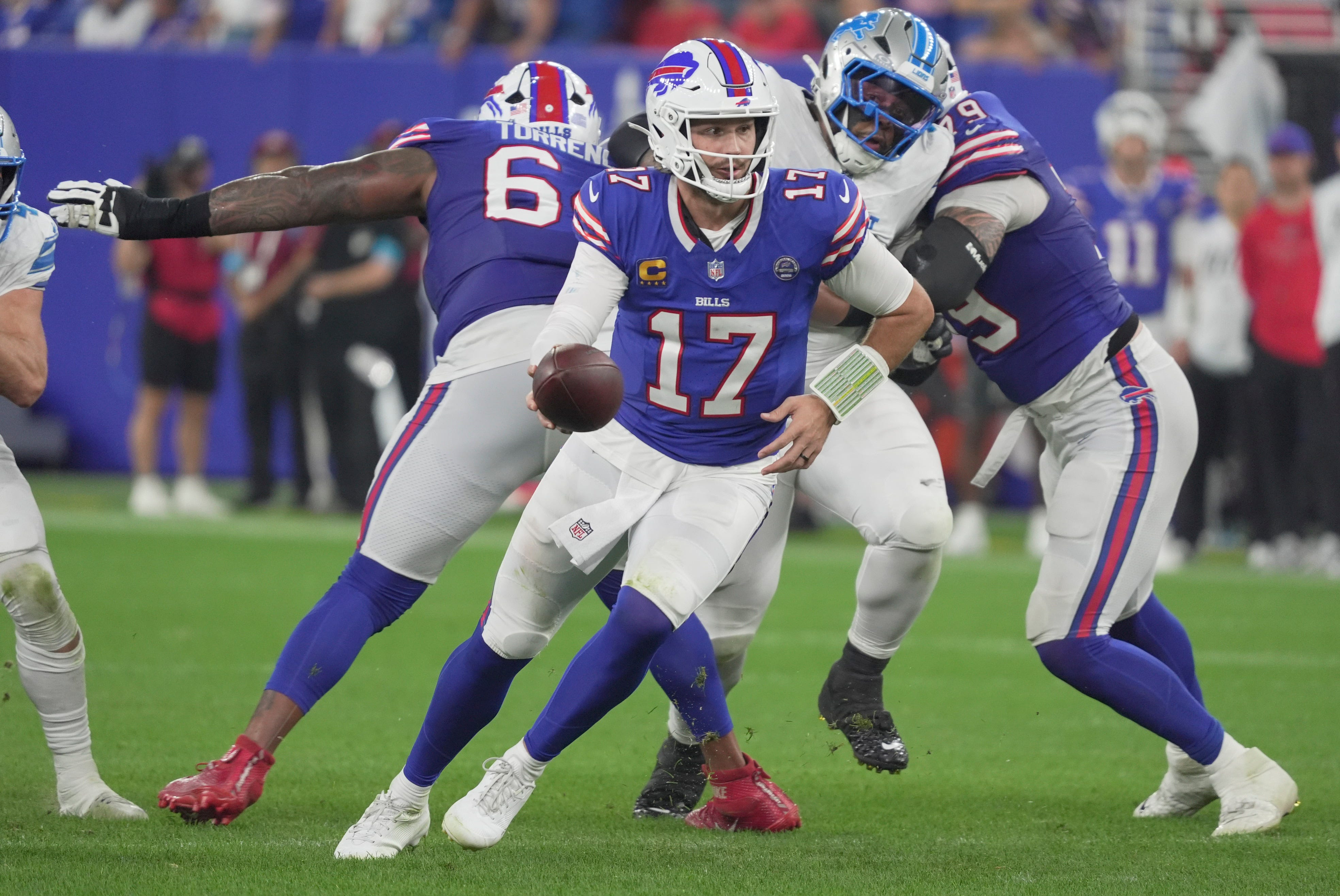 Buffalo Bills quarterback Josh Allen turns and holds out the ball as he is featured in our Chargers vs. Bills prediction.