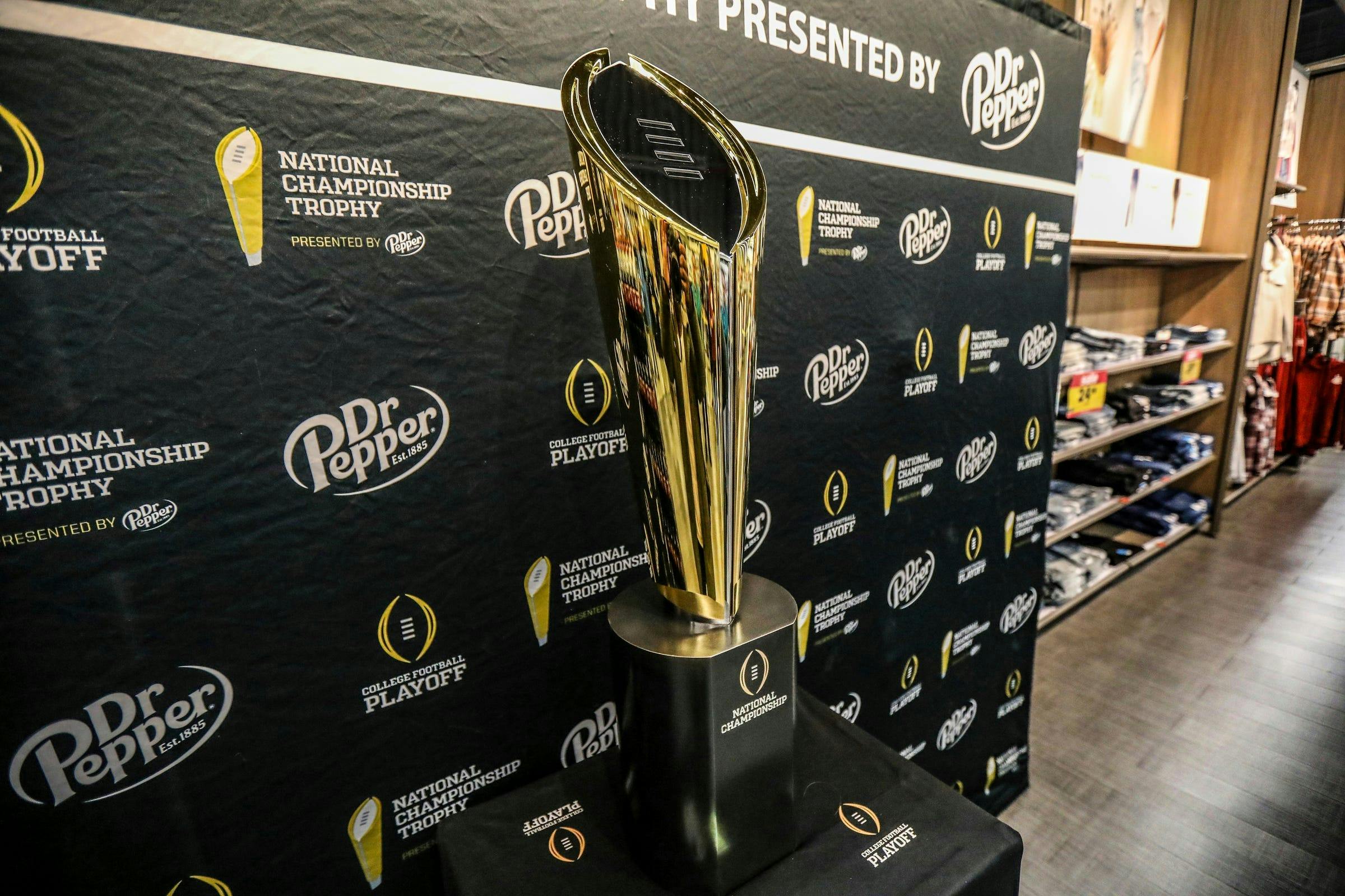 Fans stop to take photos with the College Football National Championship trophy as we look at the college football bowl game odds.