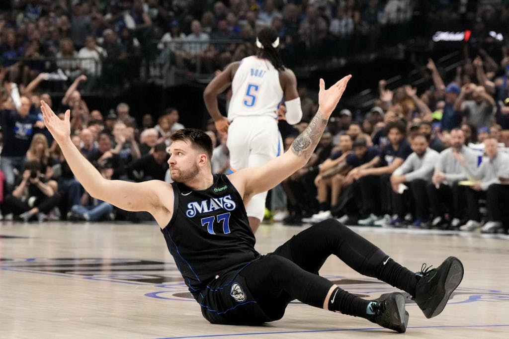 Dallas Mavericks guard Luka Doncic raises his arms while seated on the court as we look at our NBA Finals MVP odds and predictions.