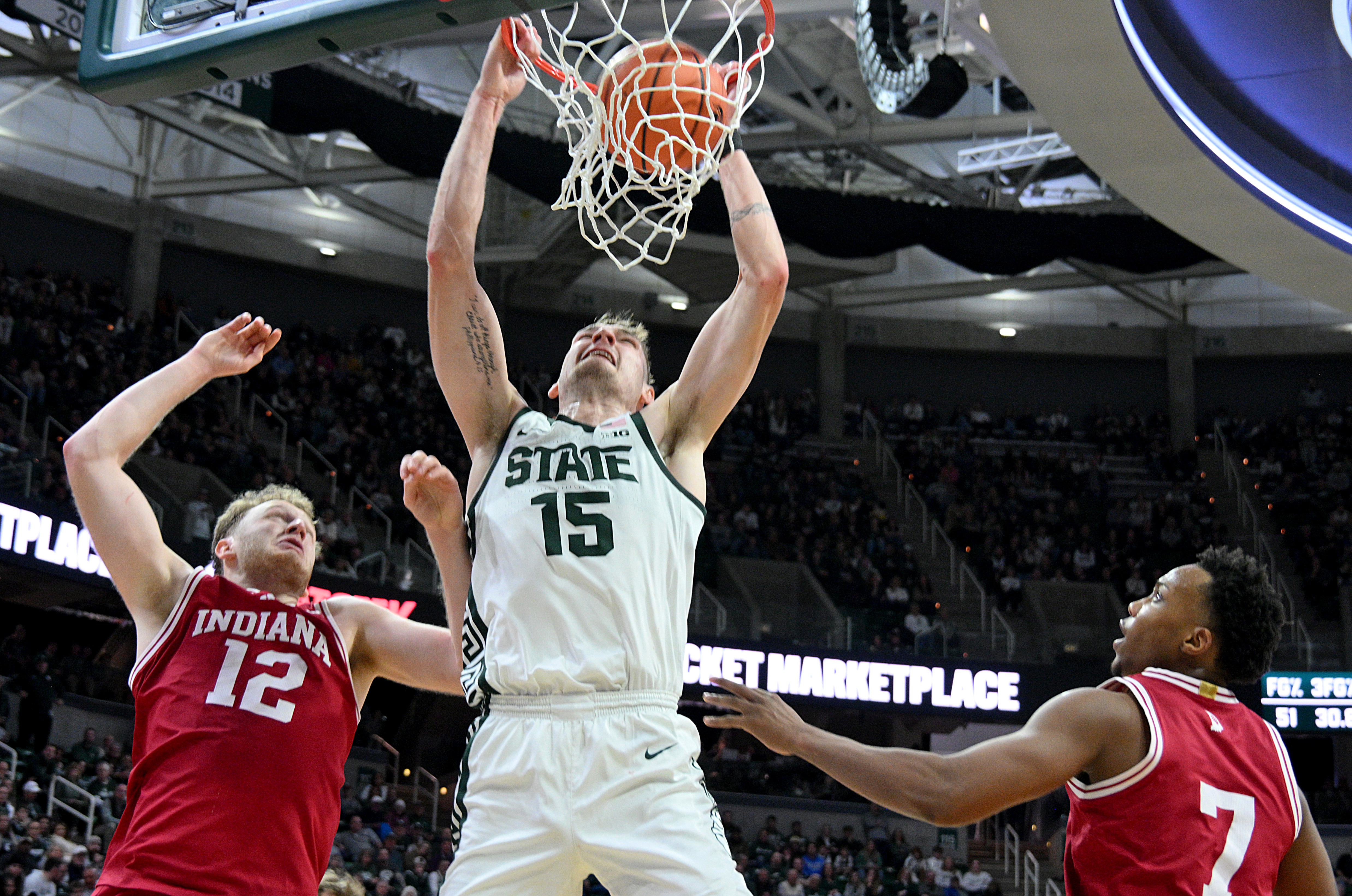 Michigan State Spartans center dunks the ball over Indiana Hoosiers Tucker Devries and Nick Dorn as we make our best Michigan State vs. Indiana prediction.