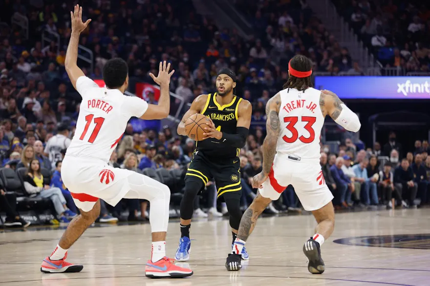 Moses Moody (4) of the Golden State Warriors looks to shoot the ball against Jontay Porter (11) and Gary Trent Jr. (33) of the Toronto Raptors, as we examine the partnership between IC360 and Radar to offer geolocation services in sports betting.