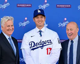 Shohei Ohtani poses with Mark Walter, owner of the Los Angeles Dodgers, and Andrew Friedman, president of baseball operations, during his introductory press conference, and we're looking at the win totals of every MLB team based on the best MLB odds.