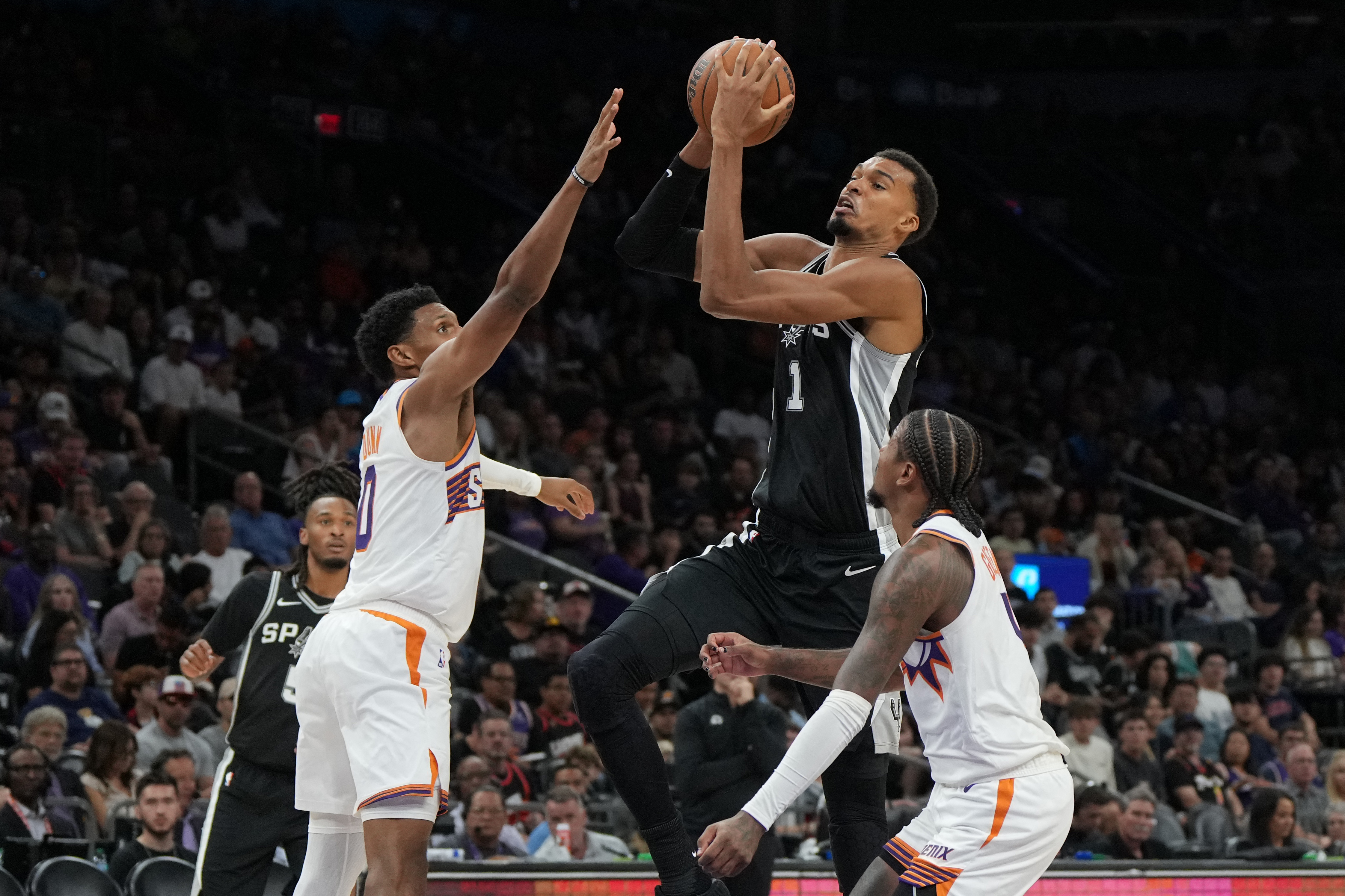 San Antonio Spurs forward Victor Wembanyama (1) drives between Phoenix Suns forward Ryan Dunn (0) and guard Jalen Green (4) as we take a closer look at the NBA Finals odds.