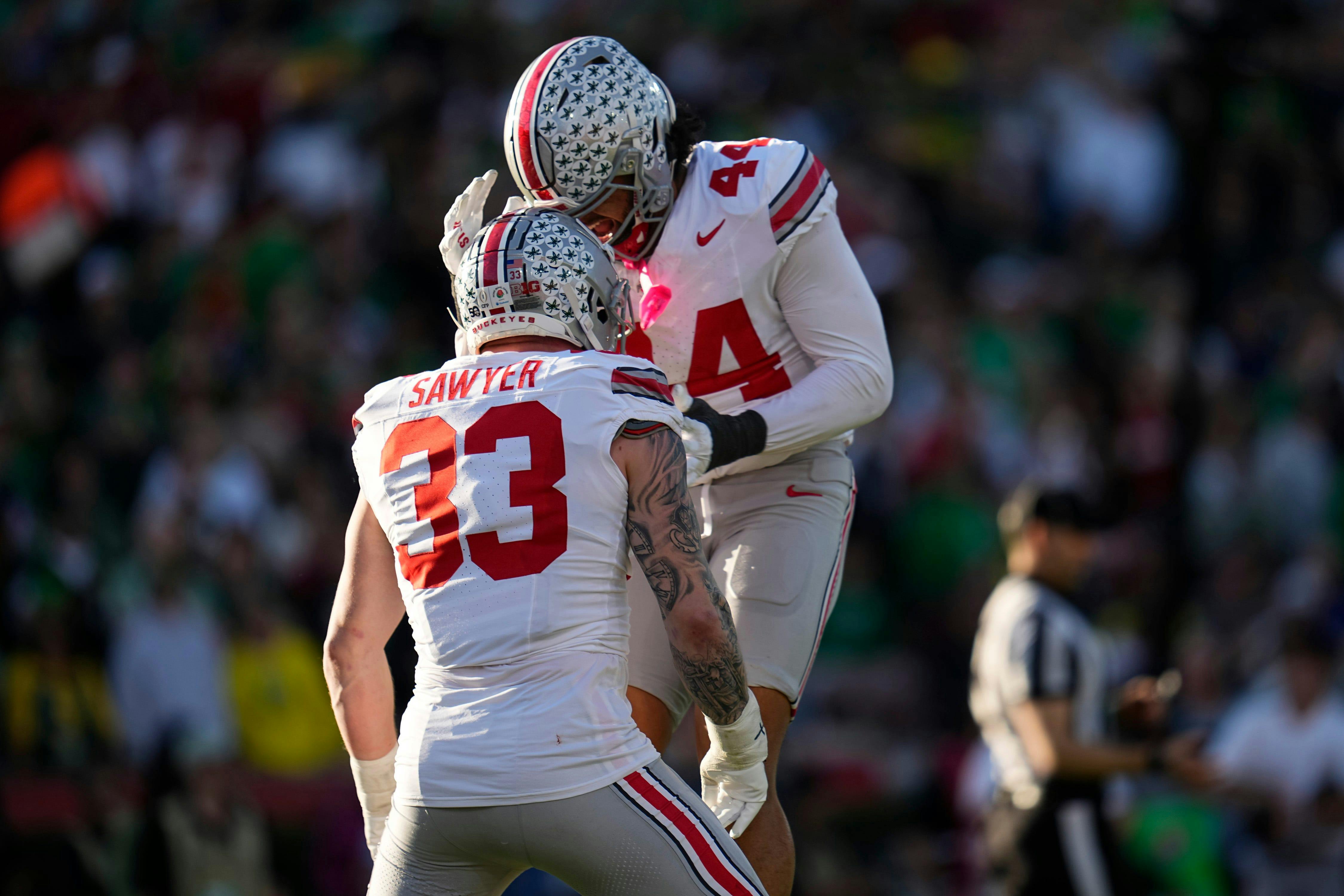 Ohio State defensive end Jack Sawyer celebrates with defensive end J.T. Tuimoloau against Oregon. We highlight Sawyer and Tuimoloau in our Ohio State football preview.