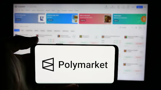 A person is holding a cellphone with the logo of Polymarket as we look at the company's reentry into the US market.