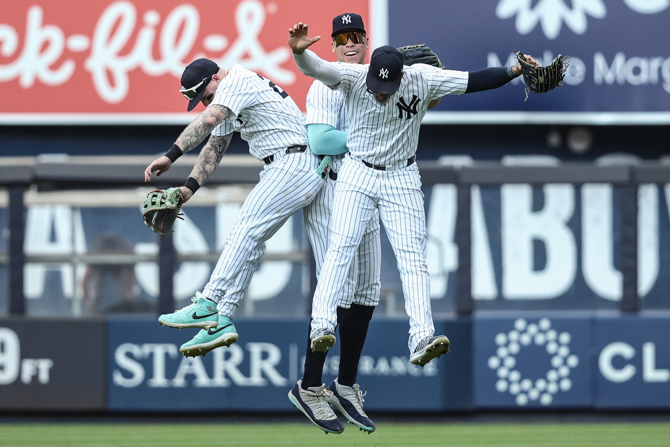New York Yankees outfielders Alex Verdugo, Aaron Judge, and Juan Soto celebrate after defeating the Colorado Rockies.