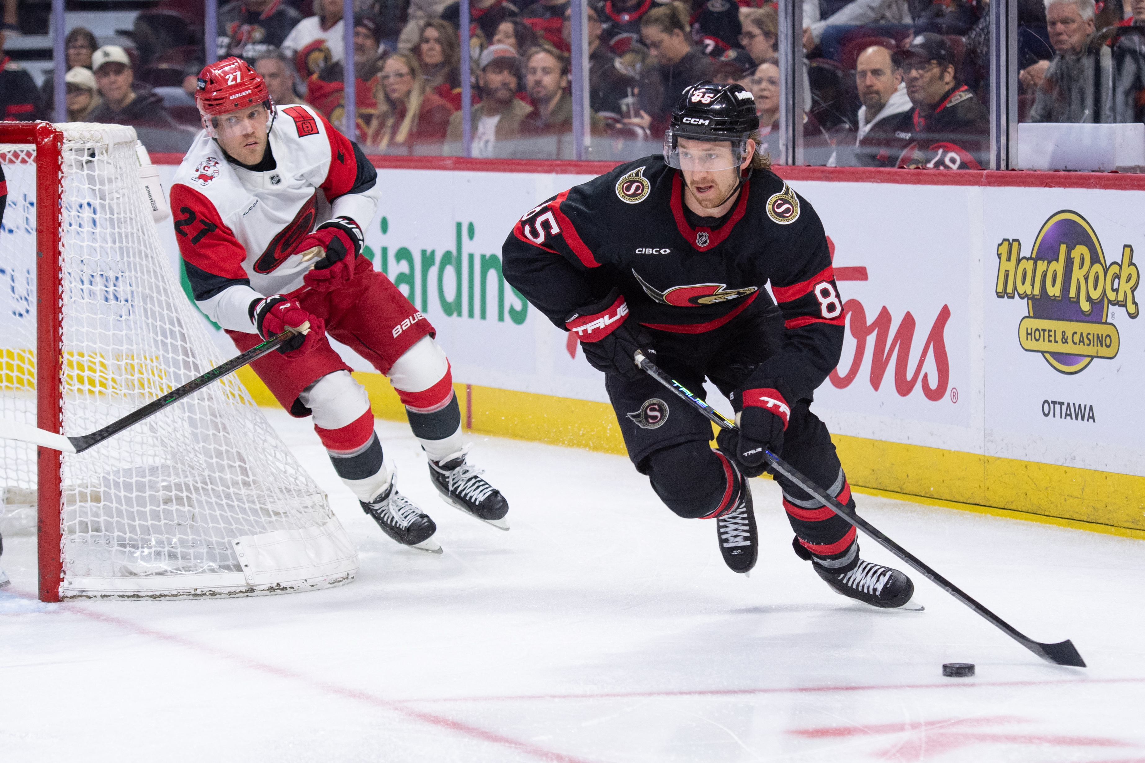 Ottawa Senators defenseman Jake Sanderson (85) skates with the puck ahead of Carolina Hurricanes winger Nikolaj Ehlers (27) as we offer our Senators vs. Hurricanes Game 1 prediction.