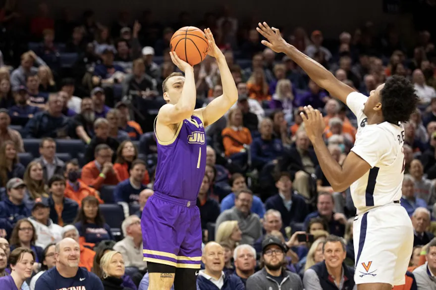 Noah Freidel #1 of the James Madison Dukes shoots over Reece Beekman #2 of the Virginia Cavaliers as we make our best March Madness upset predictions for Friday's Round 1. 