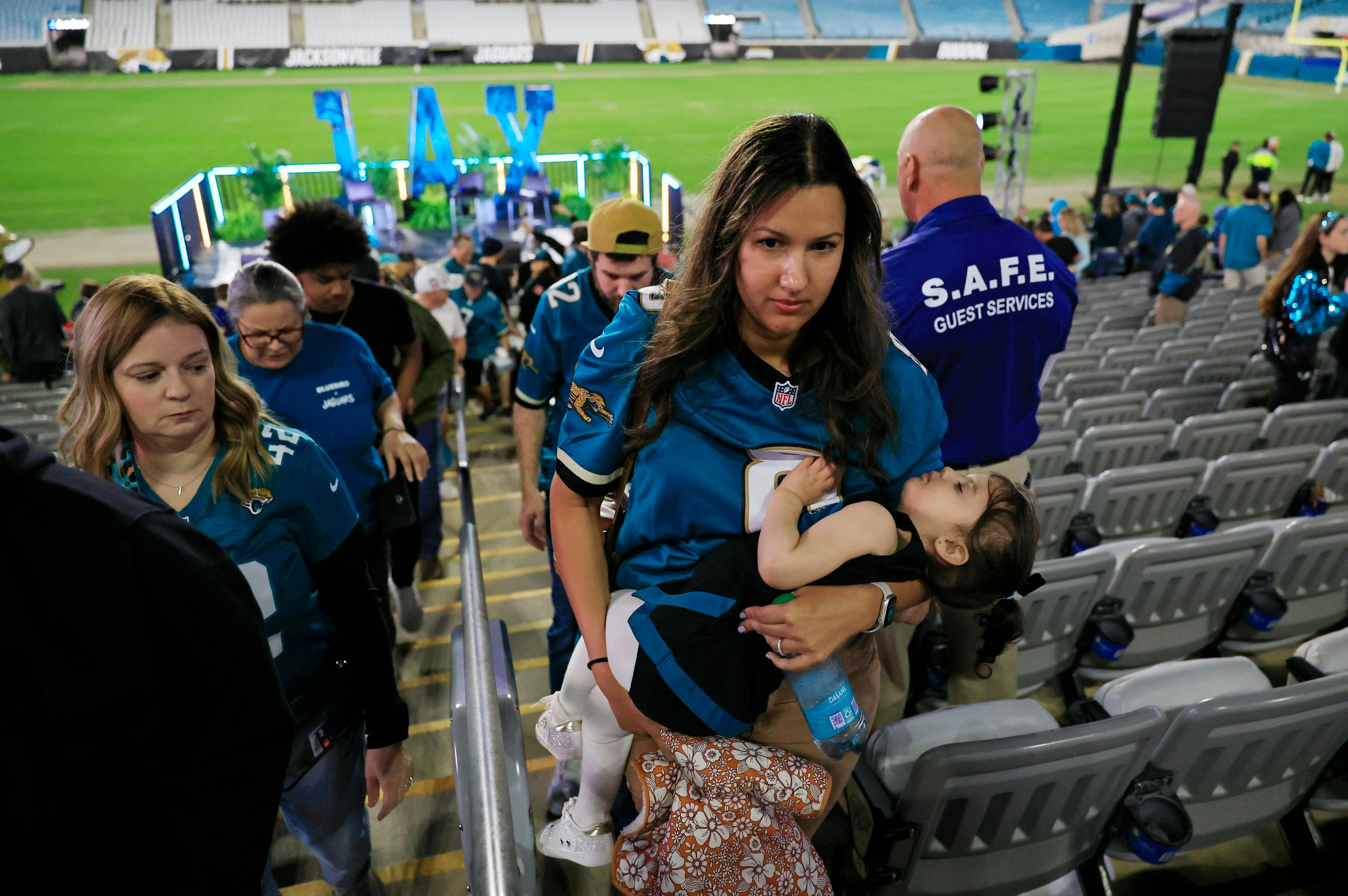 Karina Garrett carries a sleepy daughter, Lilah, 2, ahead of husband, Glenn, at EverBank Stadium.