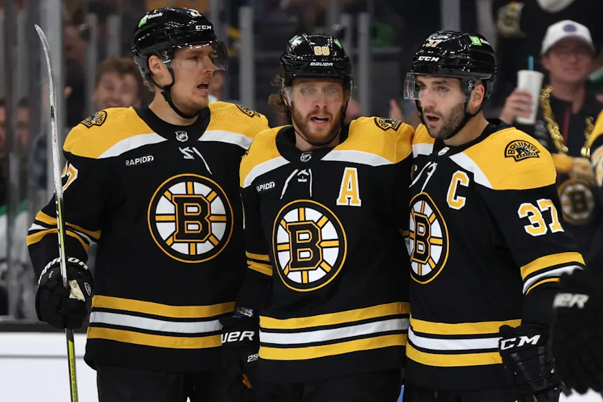 David Pastrnak of the Boston Bruins celebrates with Hampus Lindholm and Patrice Bergeron after scoring a goal against the Dallas Stars during the first period at TD Garden.