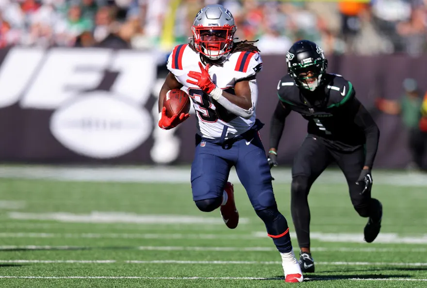 Rhamondre Stevenson #38 of the New England Patriots runs with the ball as Sauce Gardner #1 of the New York Jets defends during the first half at MetLife Stadium on October 30, 2022 in East Rutherford, New Jersey.