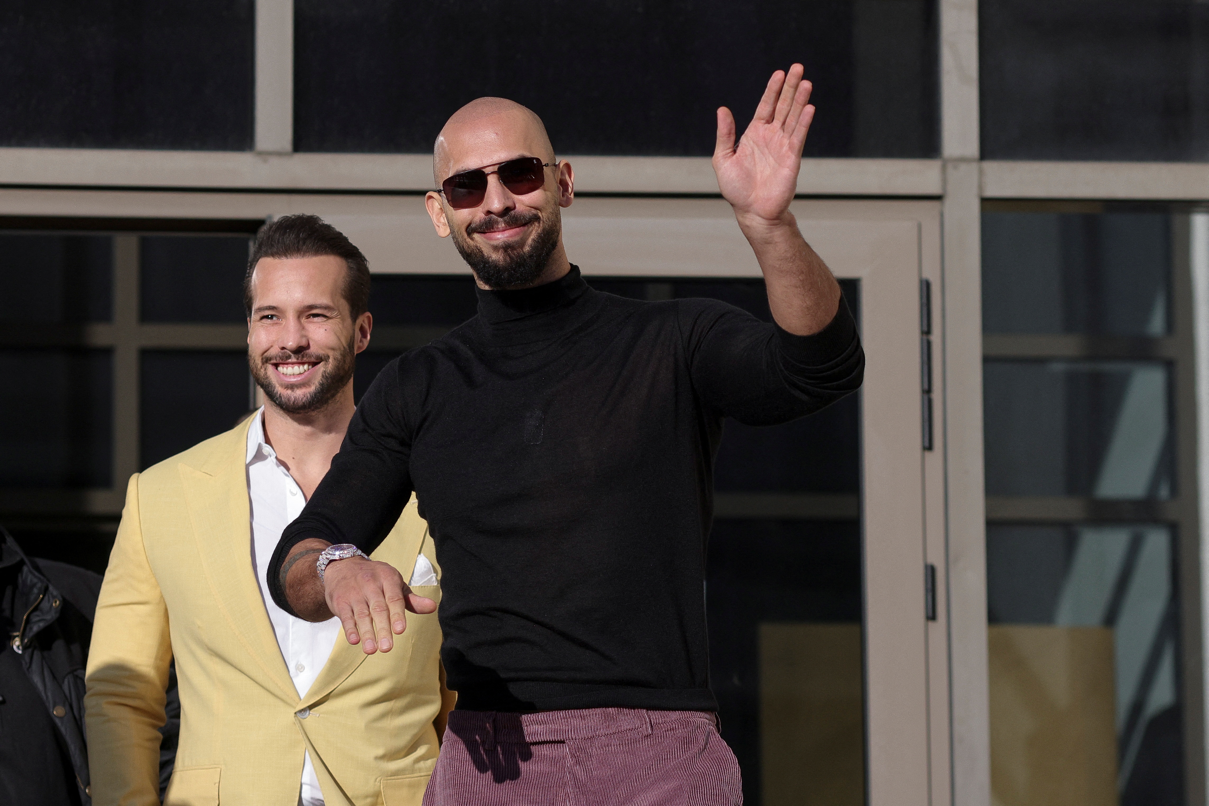 Andrew Tate waves to a crowd alongside his brother, Tristan Tate, as we look at the Andrew Tate vs. Chase DeMoor betting odds and prediction
