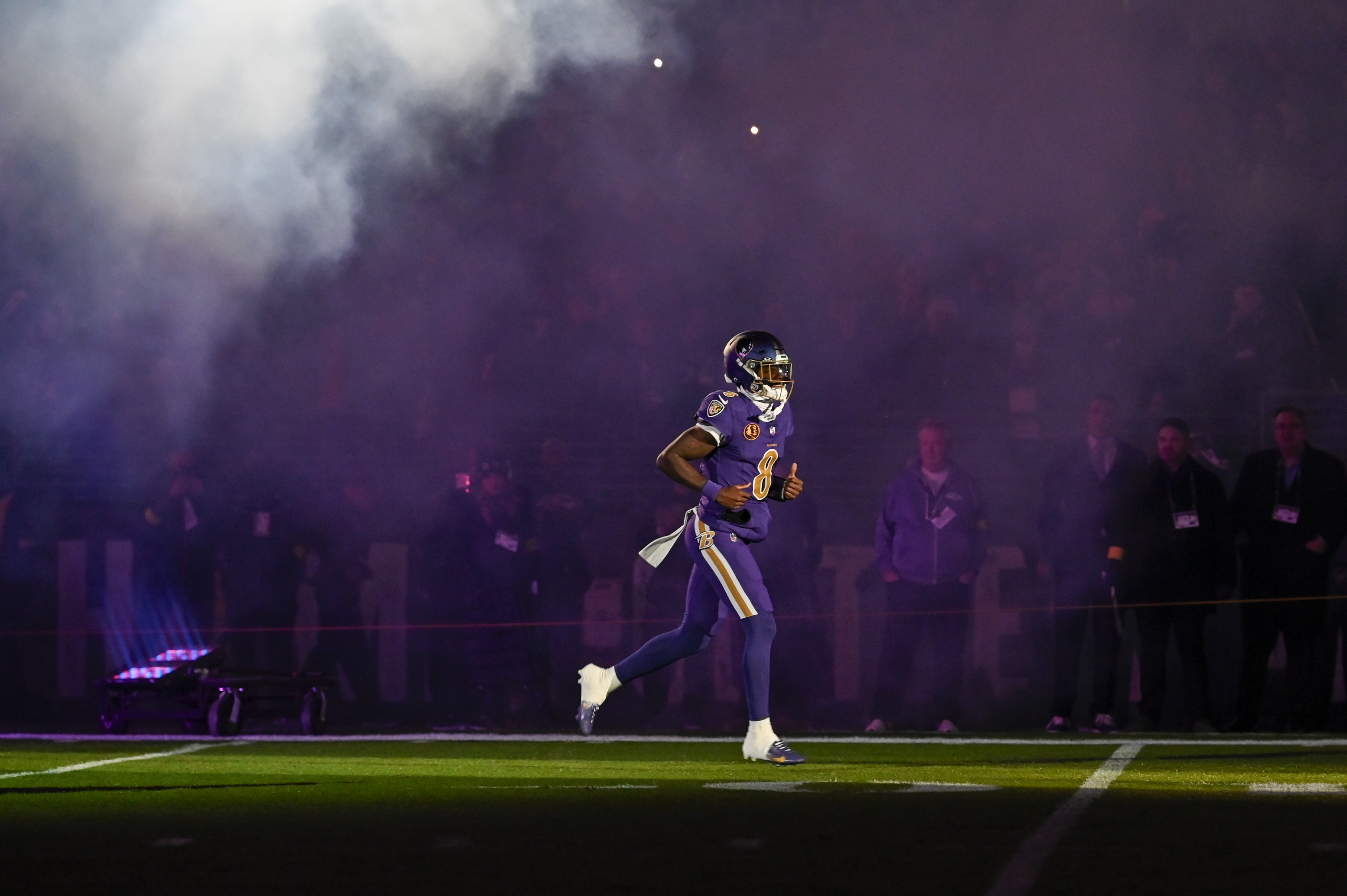 Baltimore Ravens quarterback Lamar Jackson (8) runs onto the field at M&T Bank Stadium as we break down the latest Patriots vs. Ravens weather report for Sunday Night Football.
