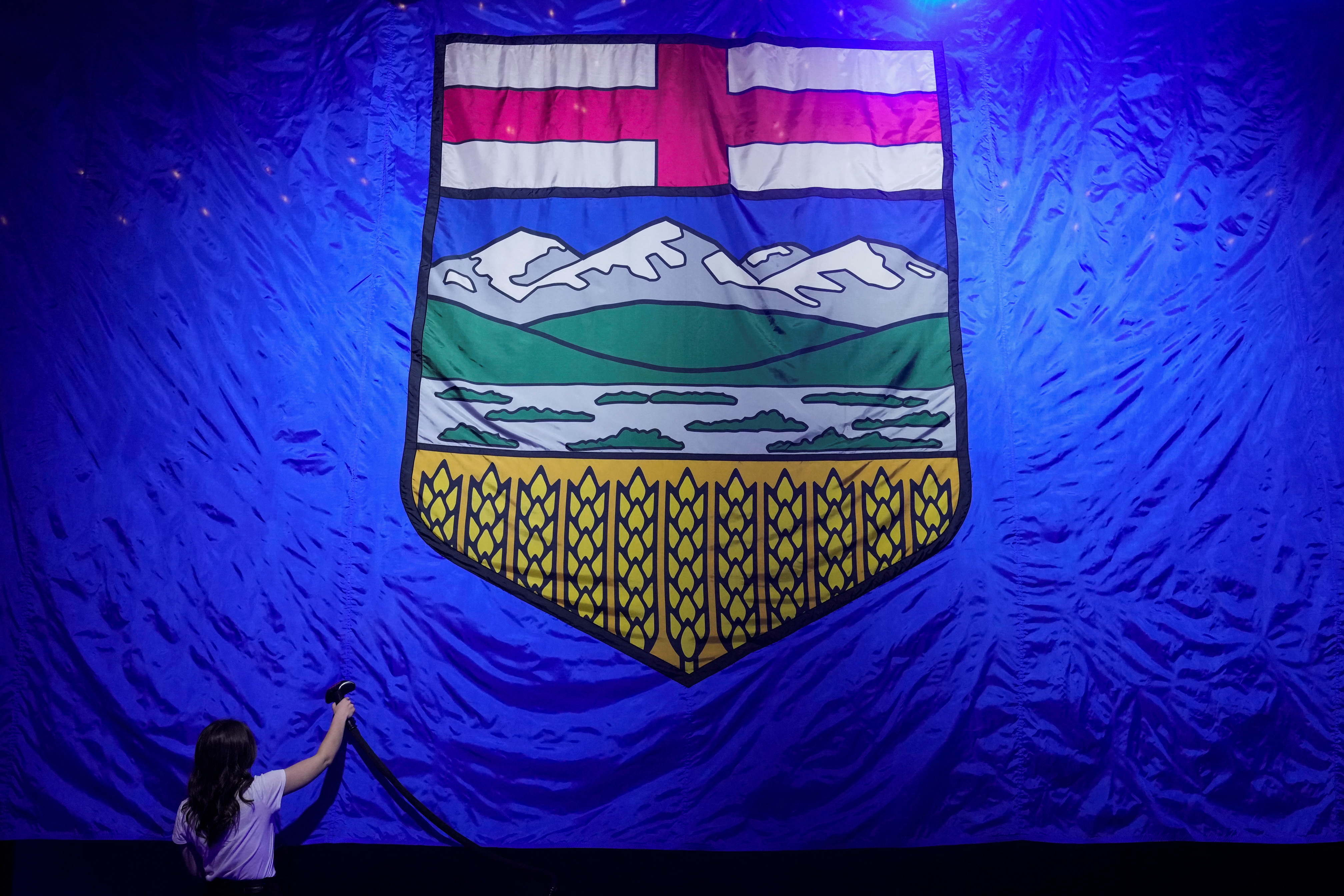 A worker irons a giant Alberta flag as we look at the province's request for proposals for gambling addiction services