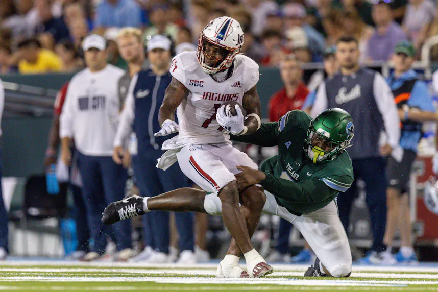 South Alabama Jaguars running back Kentrel Bullock spins to avoid the tackle of Tulane Green Wave defensive lineman Darius Hodges as we look at our college football Week 16 player prop bets.