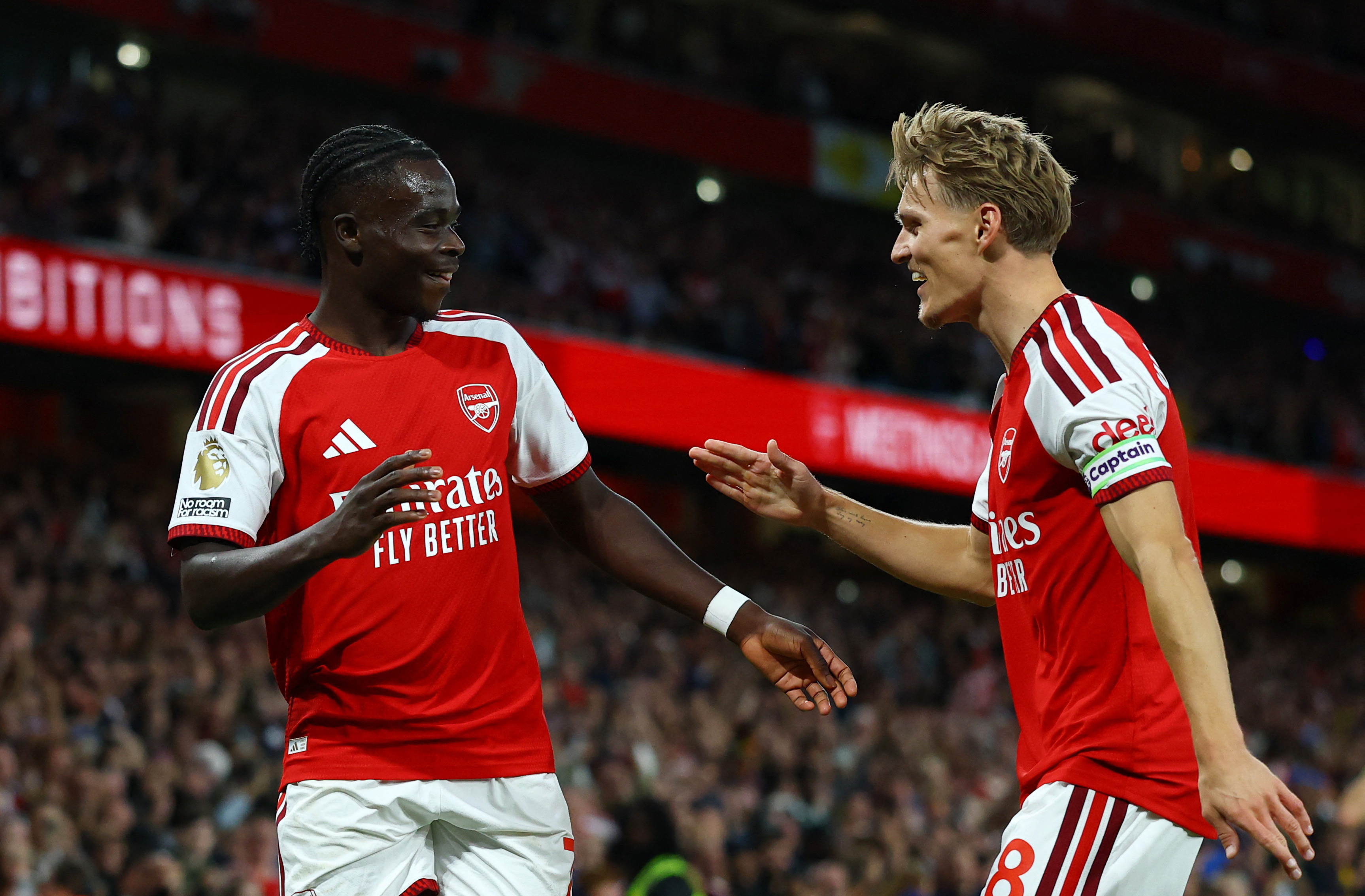Arsenal's Bukayo Saka celebrates scoring with Martin Odegaard as we make our best Aston Villa vs. Arsenal prediction. 