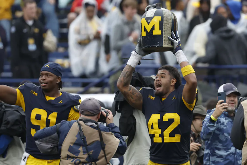 Michigan Wolverines defensive end TJ Guy lifts up the Little Brown Jug after defeating the Minnesota Golden Gophers.