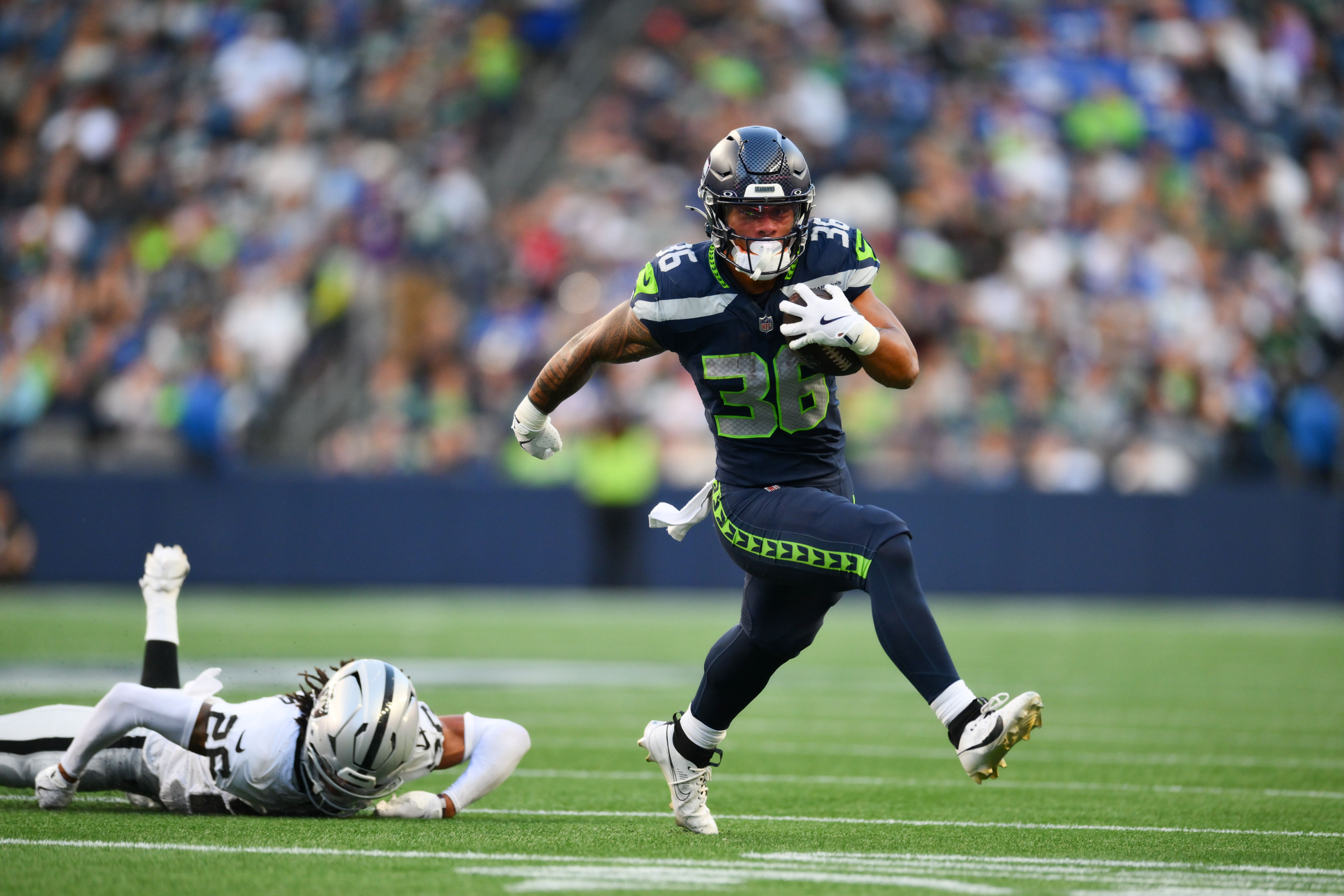 Seattle Seahawks running back George Holani (36), who is featured in our Super Bowl first touchdown predictions, breaks a tackle by Las Vegas Raiders cornerback Darien Porter (26).