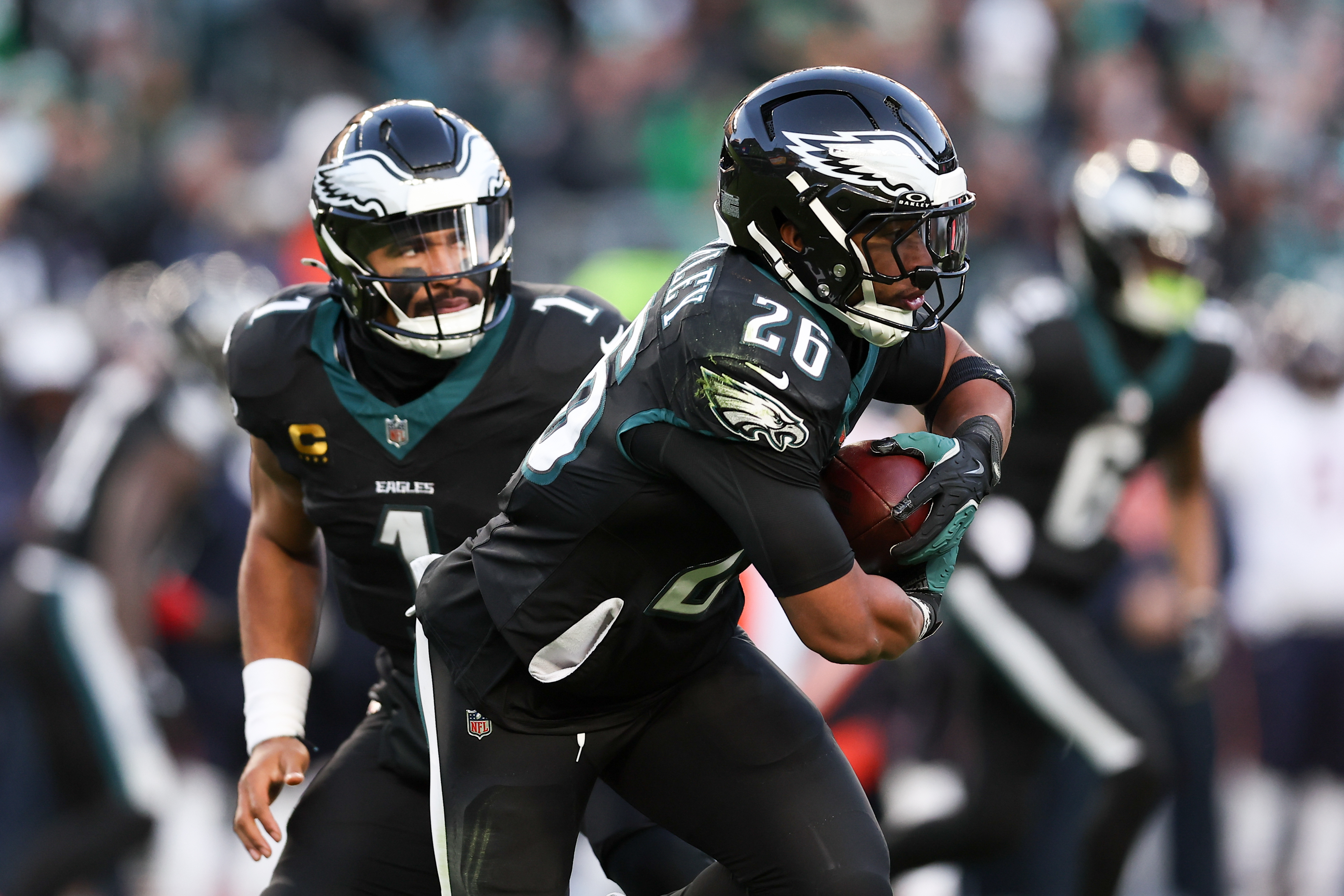 Philadelphia Eagles quarterback Jalen Hurts (1) hands the ball to Philadelphia Eagles running back Saquon Barkley (26), and both are featured in my Eagles vs. Commanders player props.