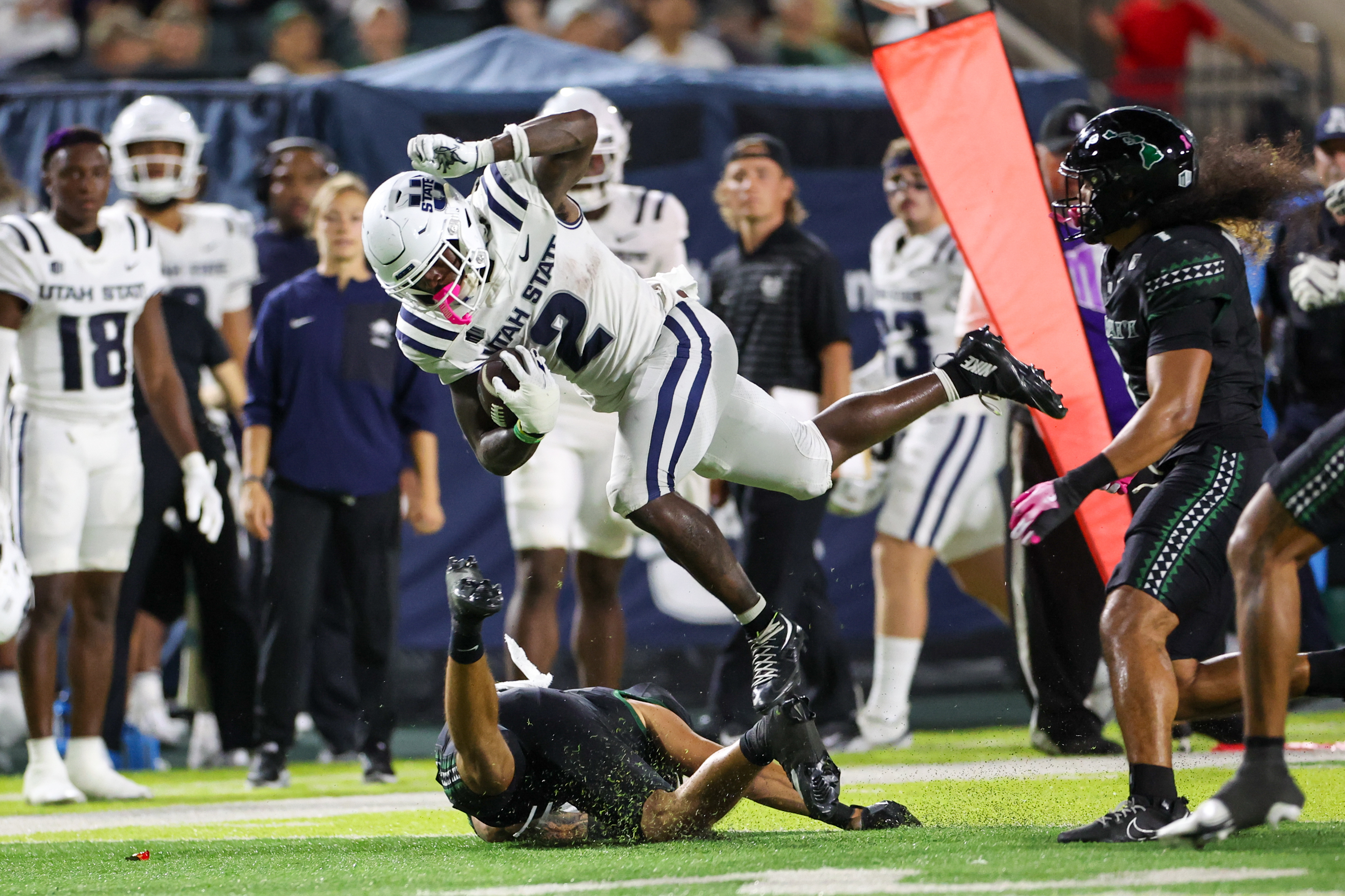 Utah State running back Miles Davis (2) leaps over a defender as we offer our Washington State vs. Utah State predictions.