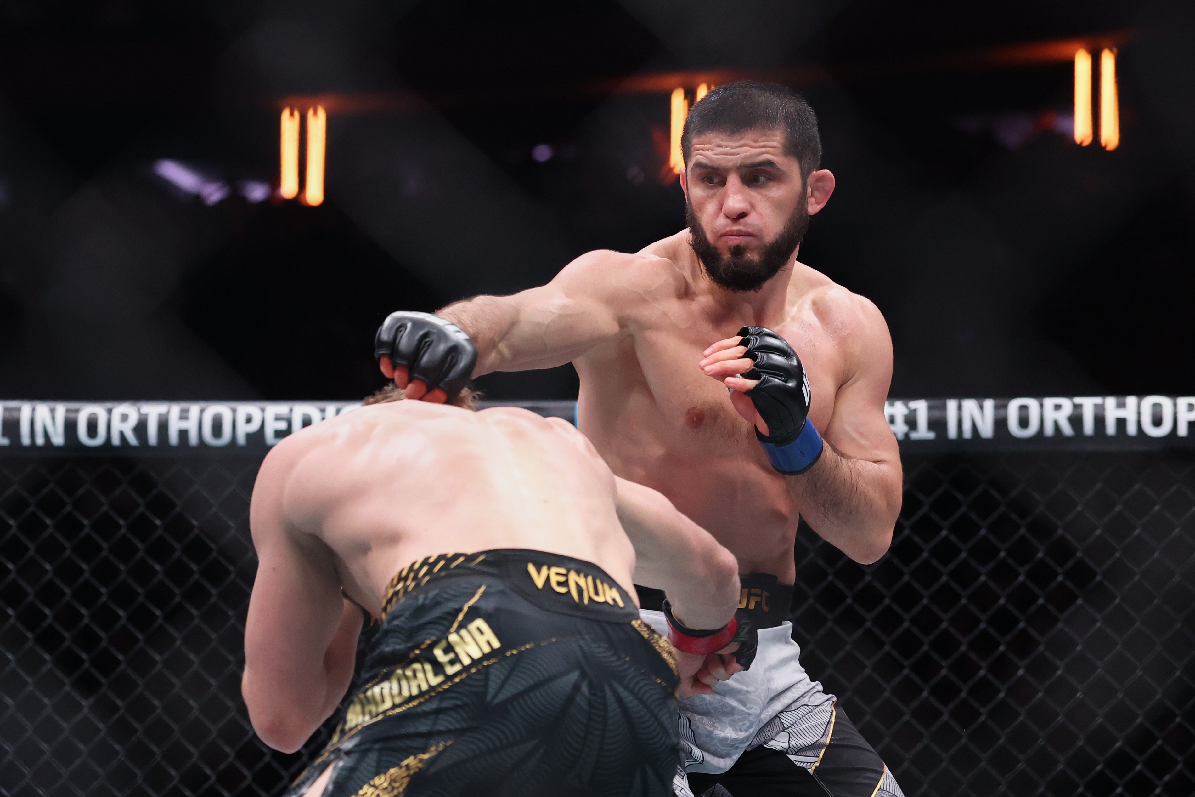 Islam Makhachev (blue gloves) fights as we break down our Makhachev vs. Garry prediction.