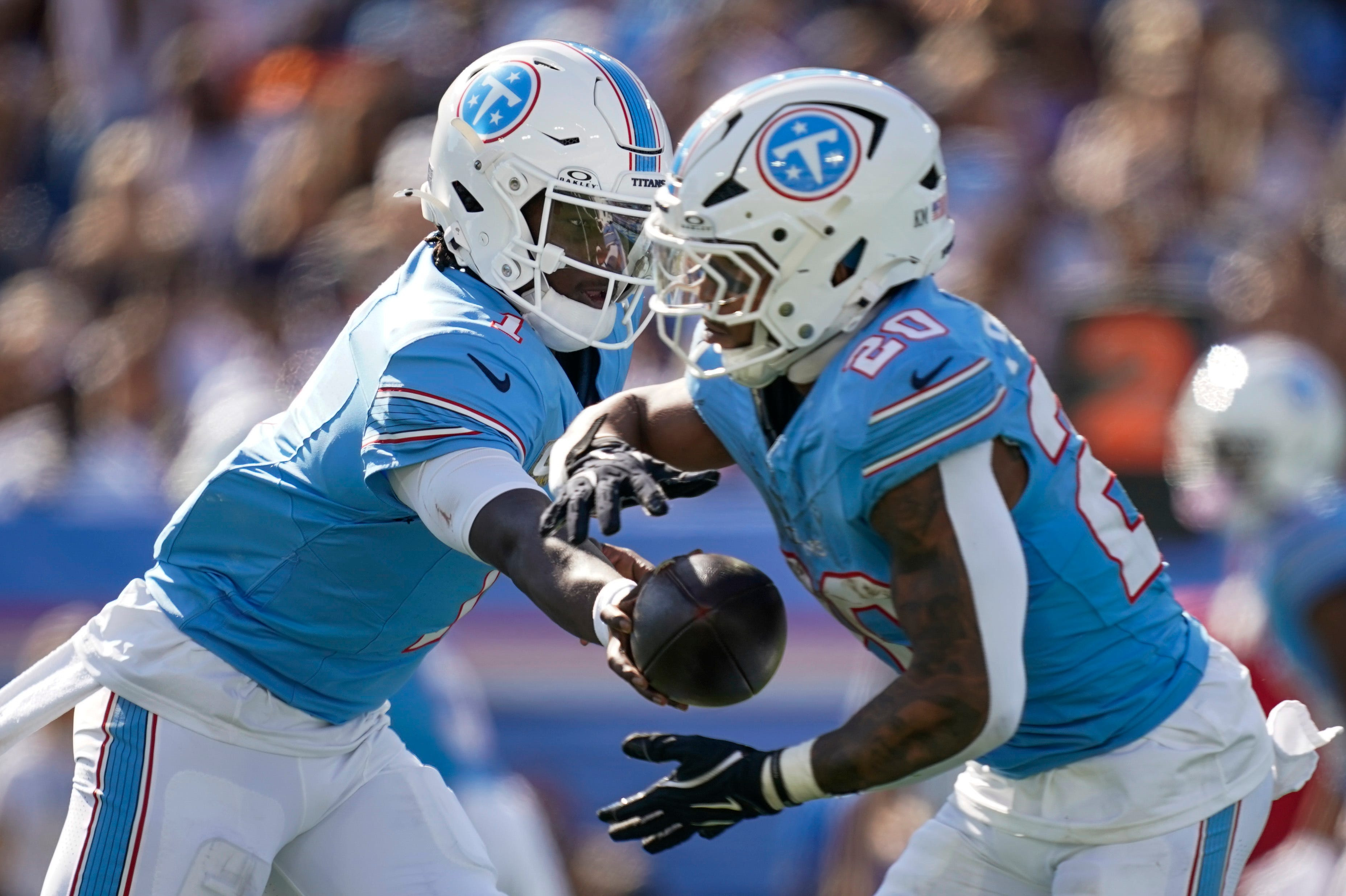 Tennessee Titans quarterback Cam Ward (1) hands off to running back Tony Pollard (20) as he is featured in our NFL anytime touchdown scorer predictions.