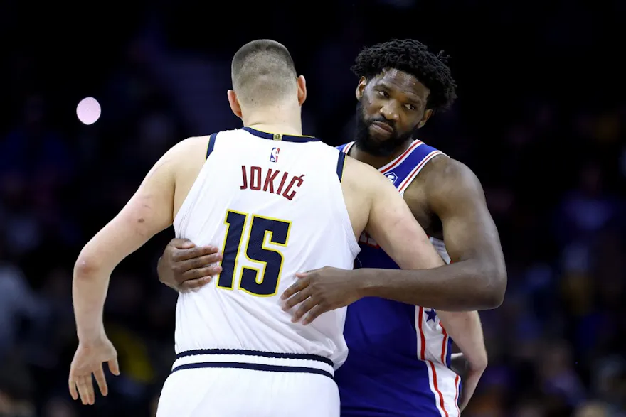 Nikola Jokic #15 of the Denver Nuggets and Joel Embiid #21 of the Philadelphia 76ers embrace as we look at our best 76ers vs. Nuggets NBA player props
