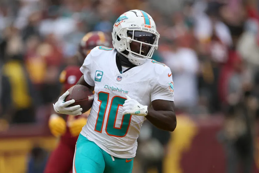 Wide receiver Tyreek Hill of the Miami Dolphins catches and runs for a touchdown pass in front of cornerback Kendall Fuller as we look at our Tyreek Hill NFL player prop picks.