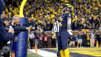 Blake Corum of the Michigan Wolverines celebrates a touchdown as look at the latest college football national championship odds.