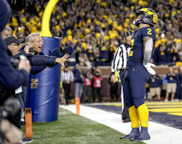 Blake Corum of the Michigan Wolverines celebrates a touchdown as look at the latest college football national championship odds.