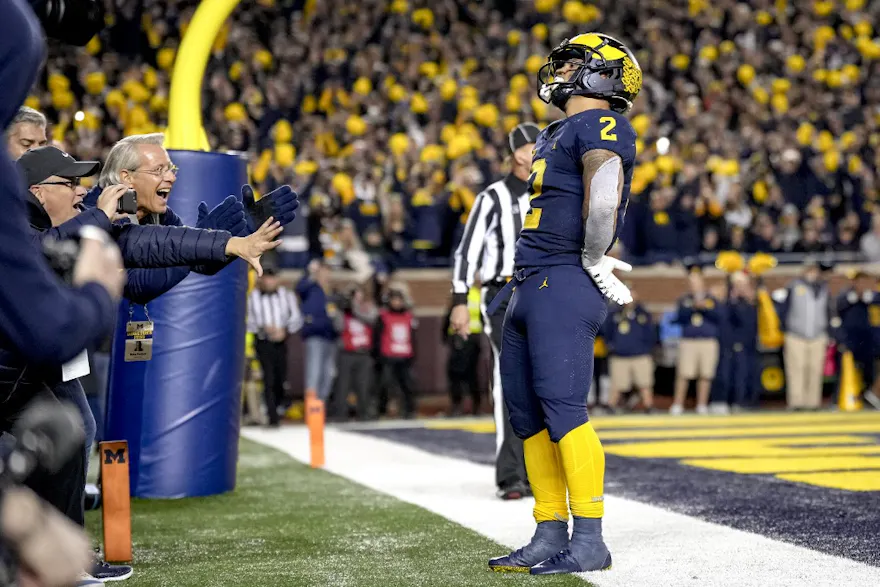 Blake Corum of the Michigan Wolverines celebrates a touchdown as look at the latest college football national championship odds.