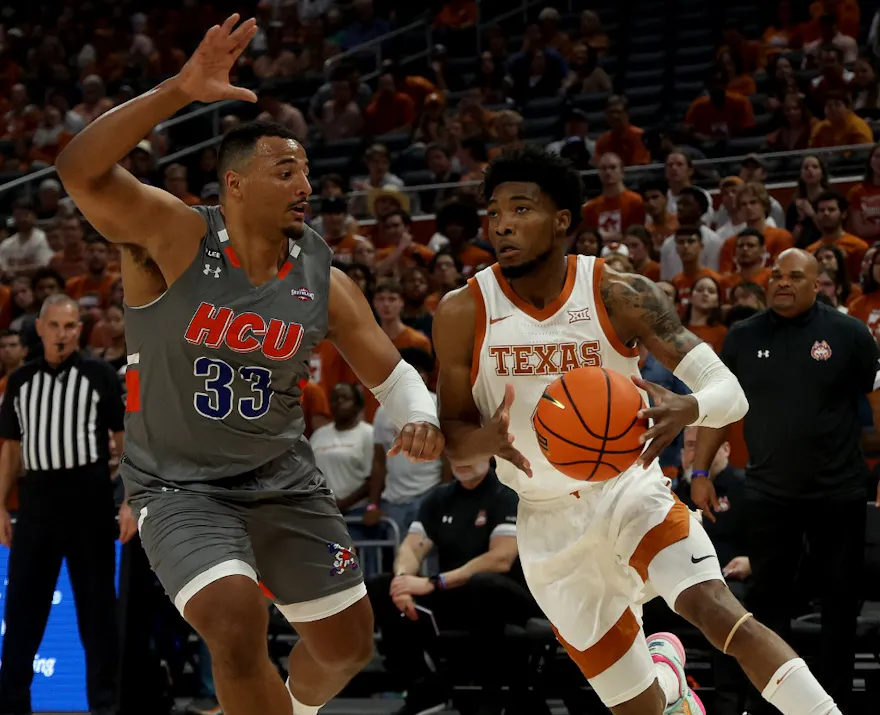 Tyrese Hunter of the Texas Longhorns drives around Sam Hofman of the Houston Christian Huskies in the first half of the game between the Houston Christian Huskies and the Texas Longhorns.