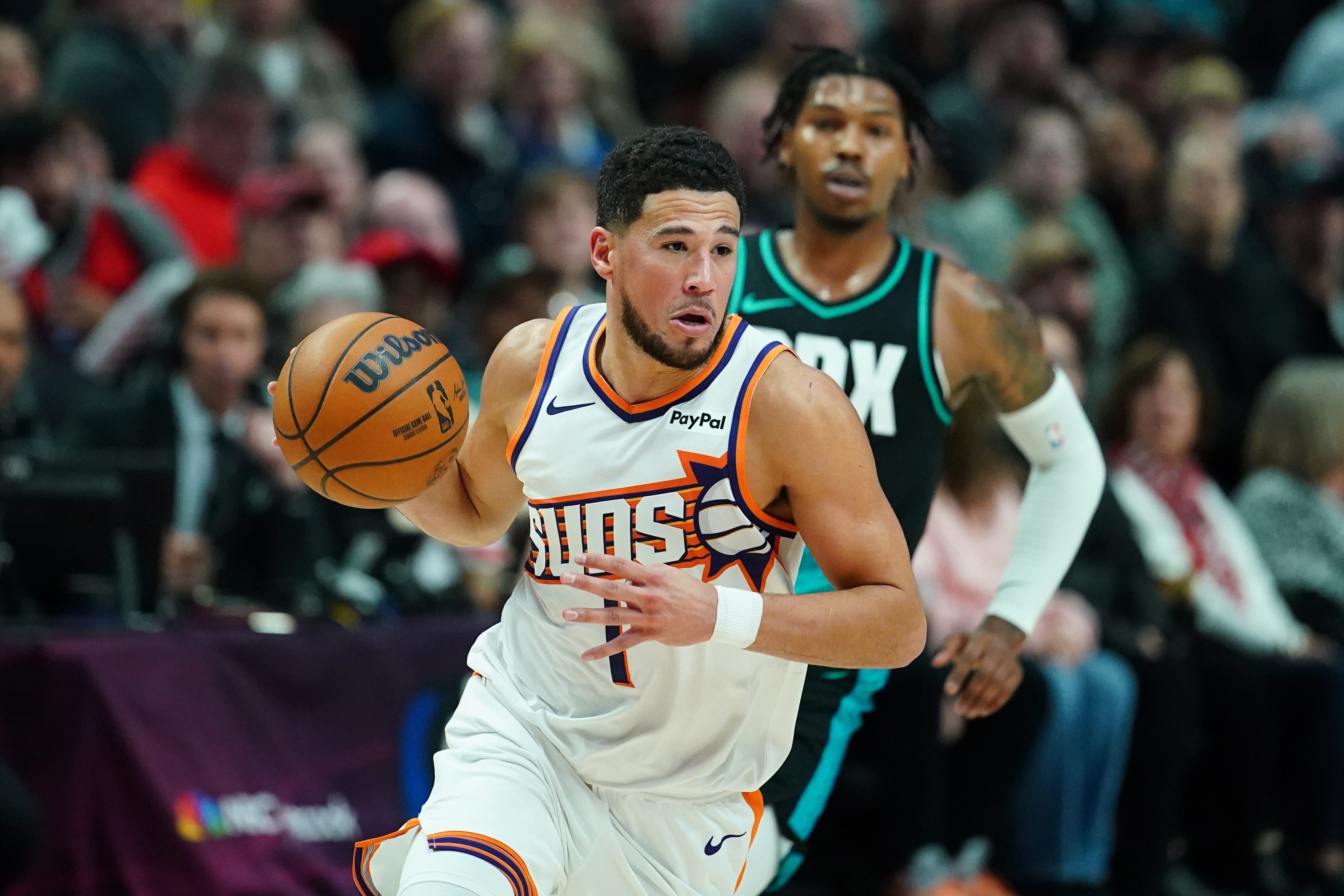 Phoenix Suns guard Devin Booker dribbles the ball as we make our best Trail Blazers vs. Suns prediction.