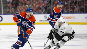 Connor McDavid skates the puck past Blake Lizotte as we provide our best prop picks and predictions for Game 1 of the second-round series between the Edmonton Oilers and Vancouver Canucks. 