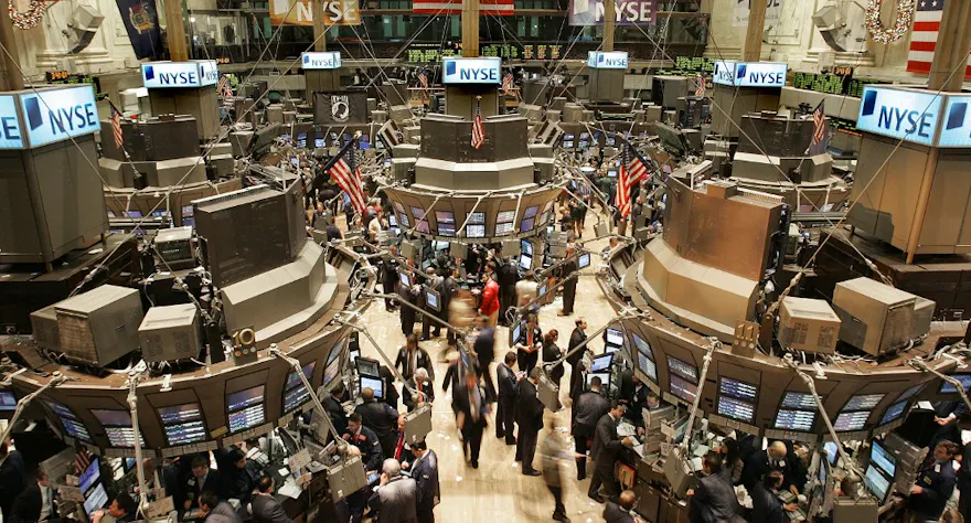Traders work on the floor of the New York Stock Exchange as we examine Flutter Entertainment's move to the New York Stock Exchange.