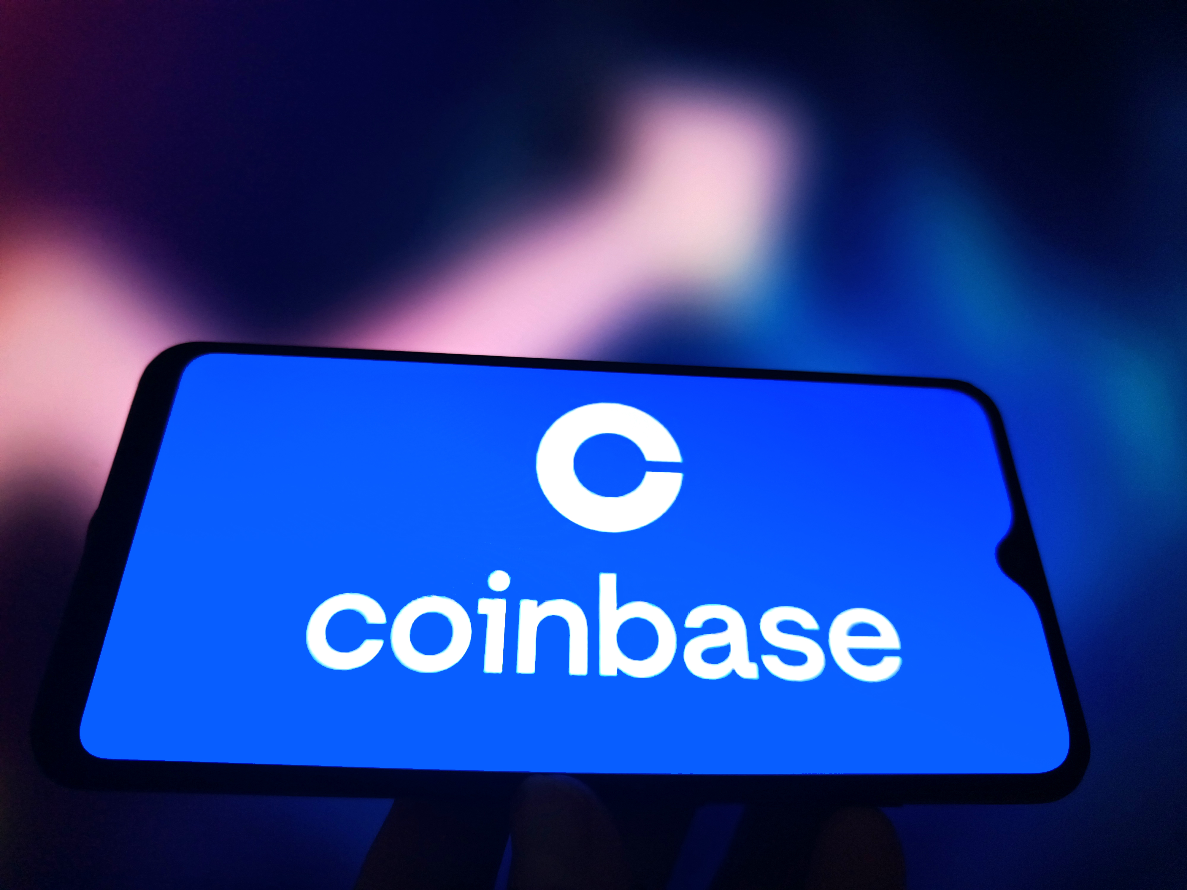 An illustration shows Coinbase logo in a smartphone as we look at its plan to launch prediction markets.