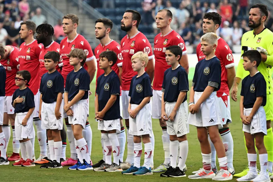 Wrexham AFC players stand for the national anthem before a pre-season friendly, and we offer new U.S. bettors our exclusive BetRivers promo code for Wrexham vs. Wigan.