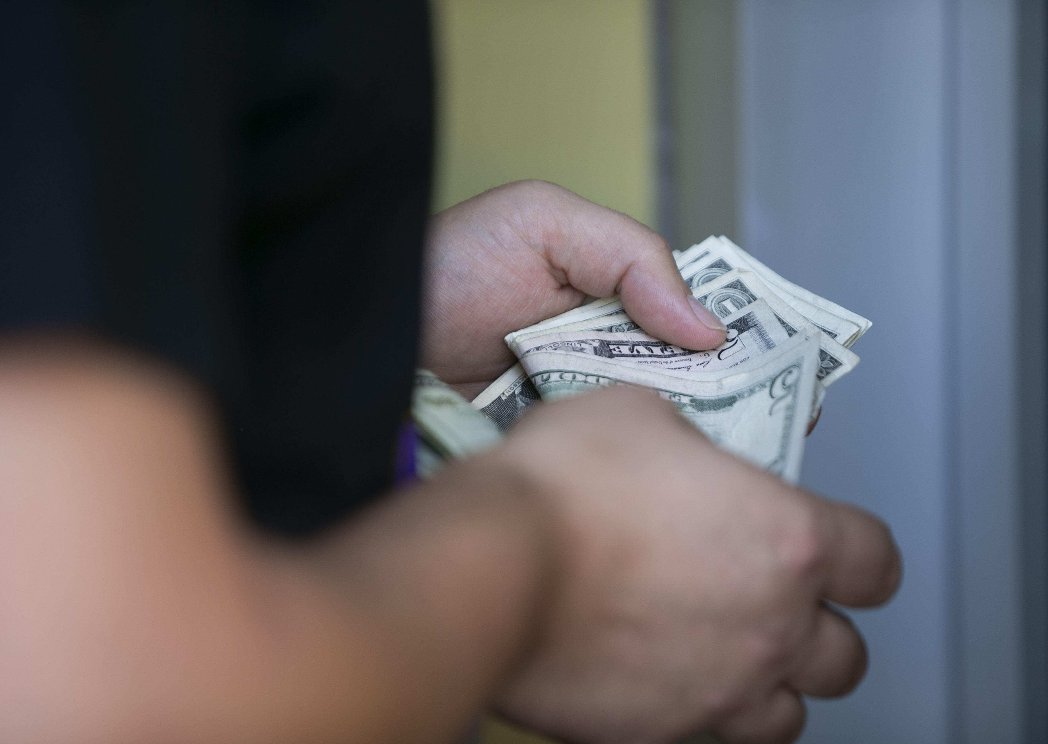 A man counts his money while placing a bet as we look at Kalshi removing sportsbook language from job postings