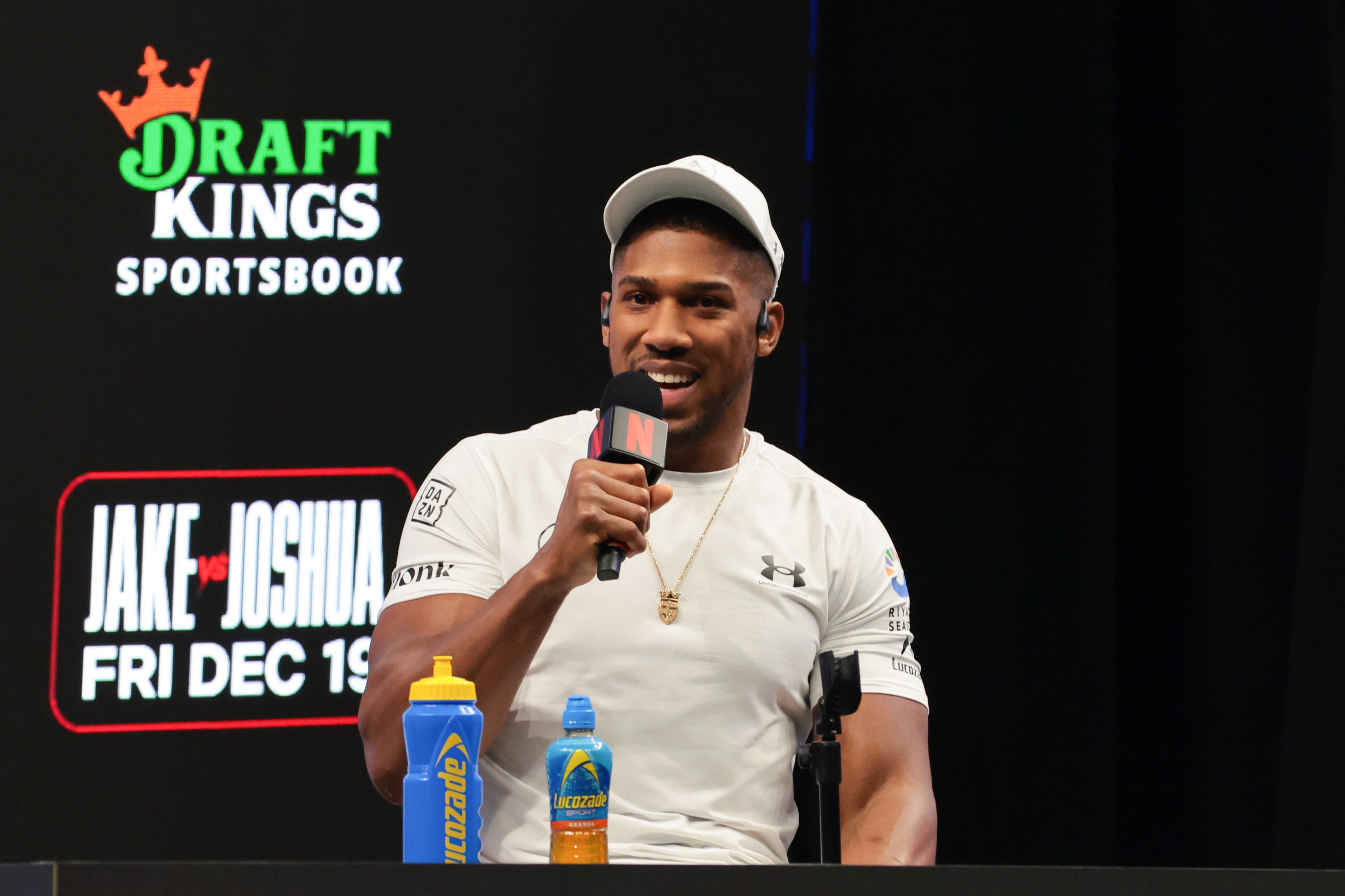 Anthony Joshua speaks to reporters during a press conference as we offer the Jake Paul vs. Anthony Joshua odds, betting lines, and prediction.