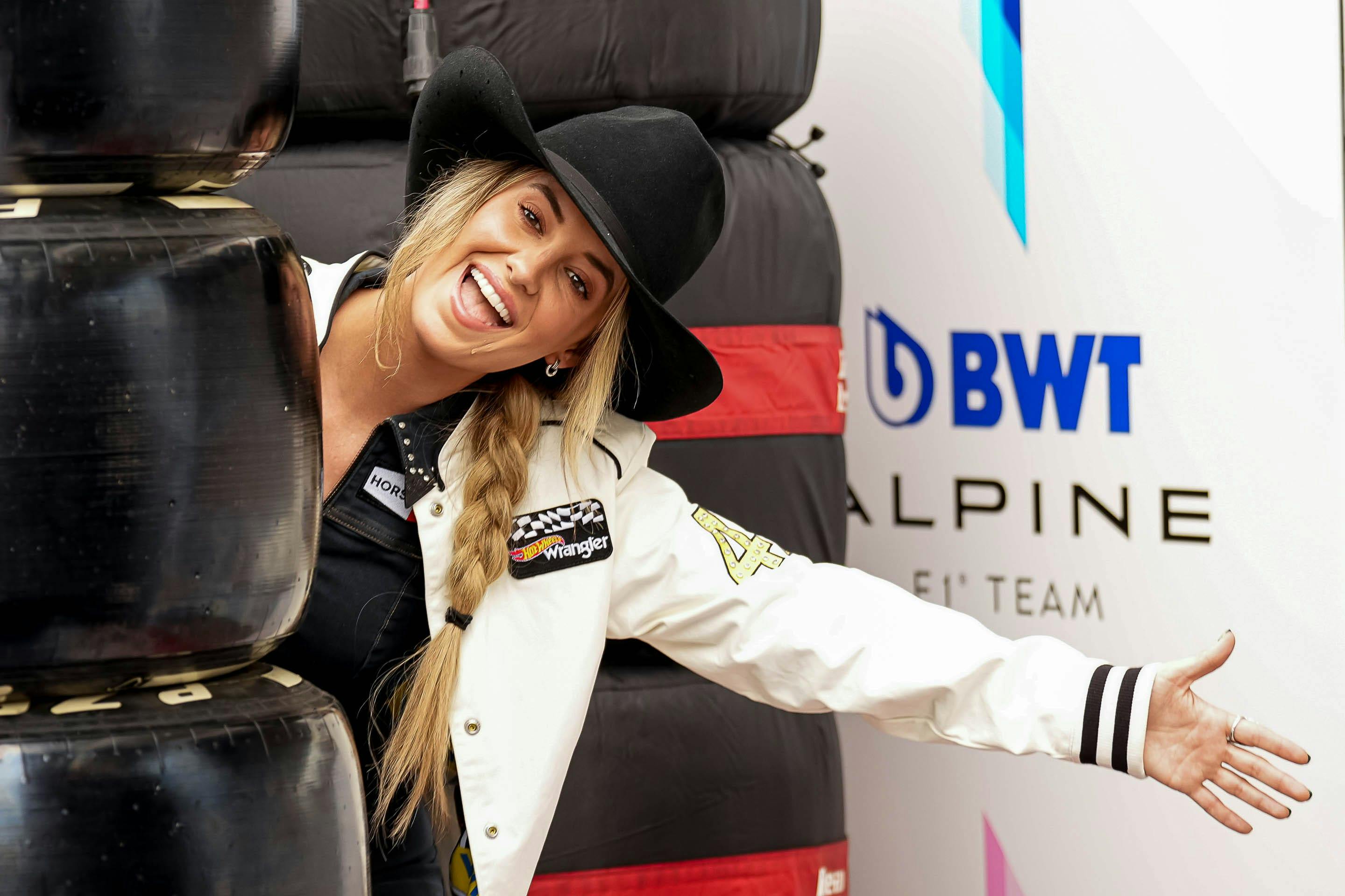 Lainey Wilson leans out of behind a stack of tires in the paddock at the Formula 1 Pirelli United States Grand Prix at Circuit of the Americas.