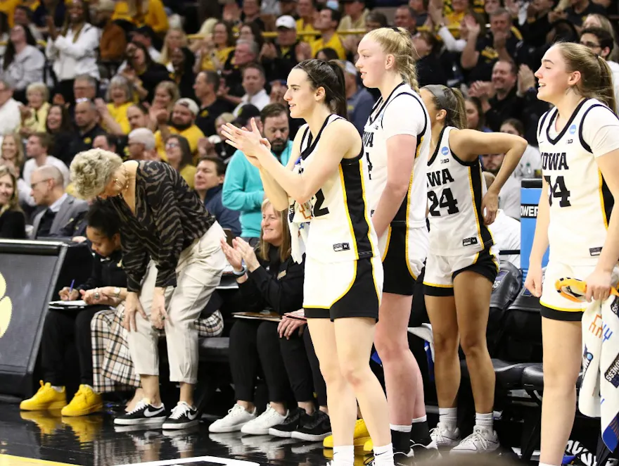 Guard Caitlin Clark #22 of the Iowa Hawkeyes cheers on teammates as we make our West Virginia vs. Iowa prediction and pick for the second round of the NCAA Tournament.